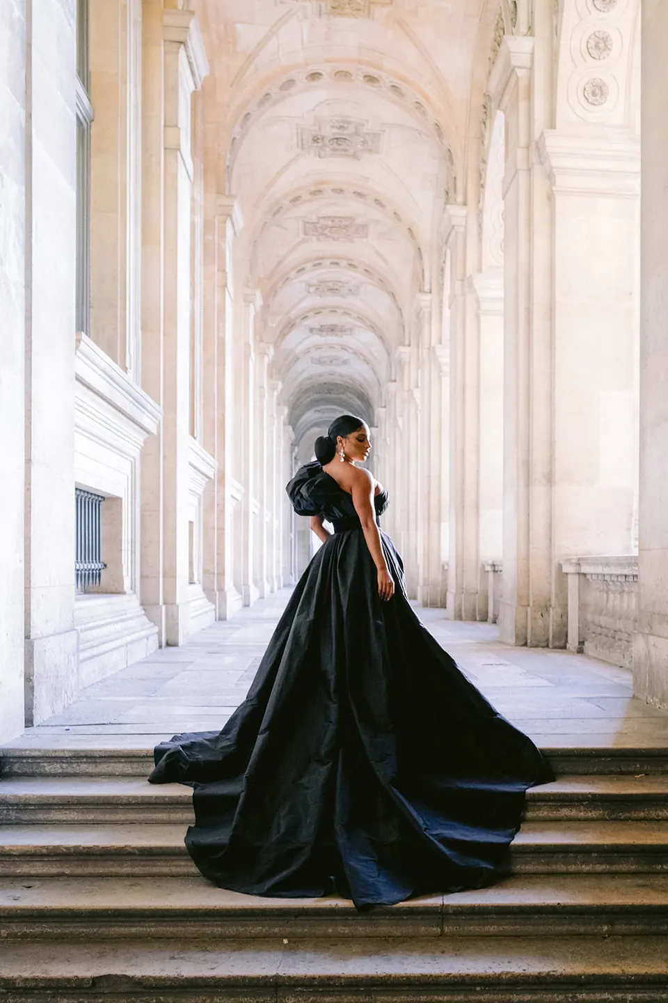 Femme en robe noire dans une galerie à l’architecture classique