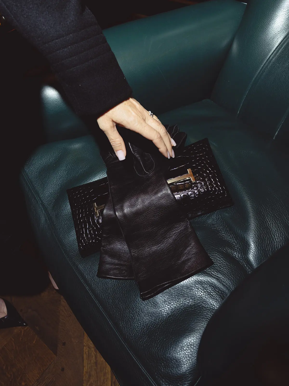 Sac et accessoires Tom Ford disposés sur un fauteuil en cuir vert