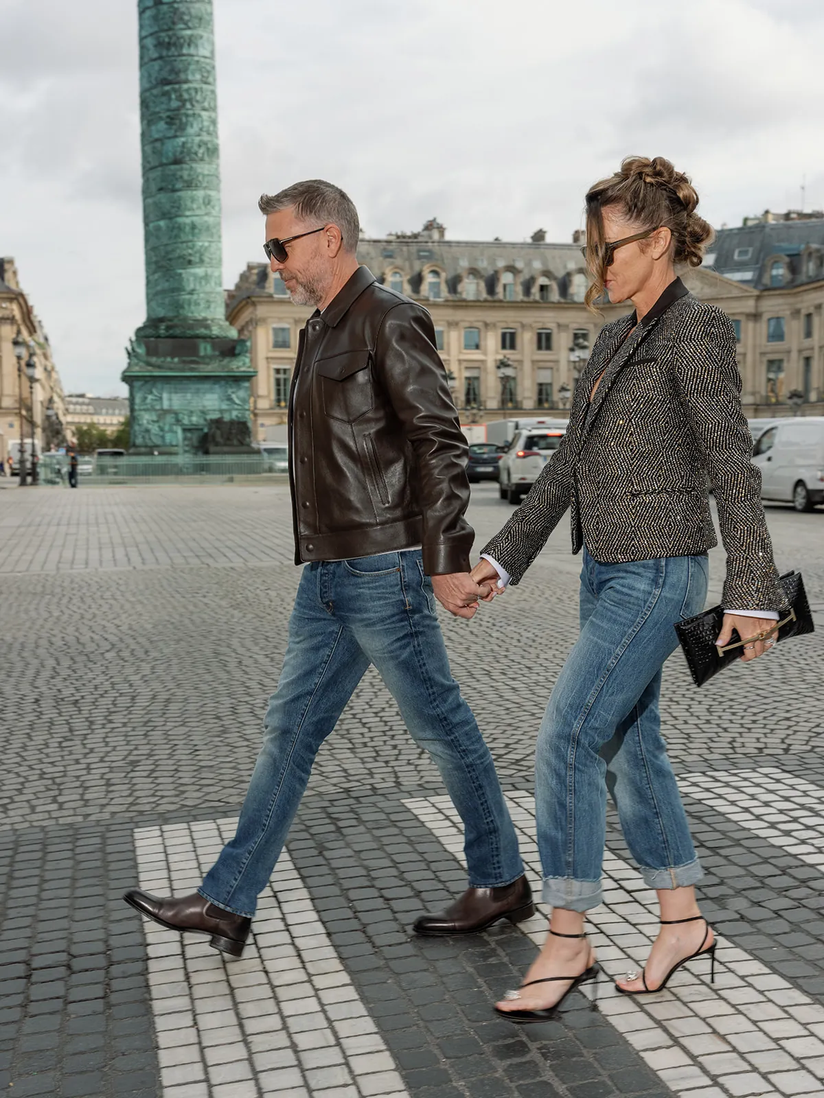 Two people walking hand in hand beside the Vendôme Column in denim and jackets