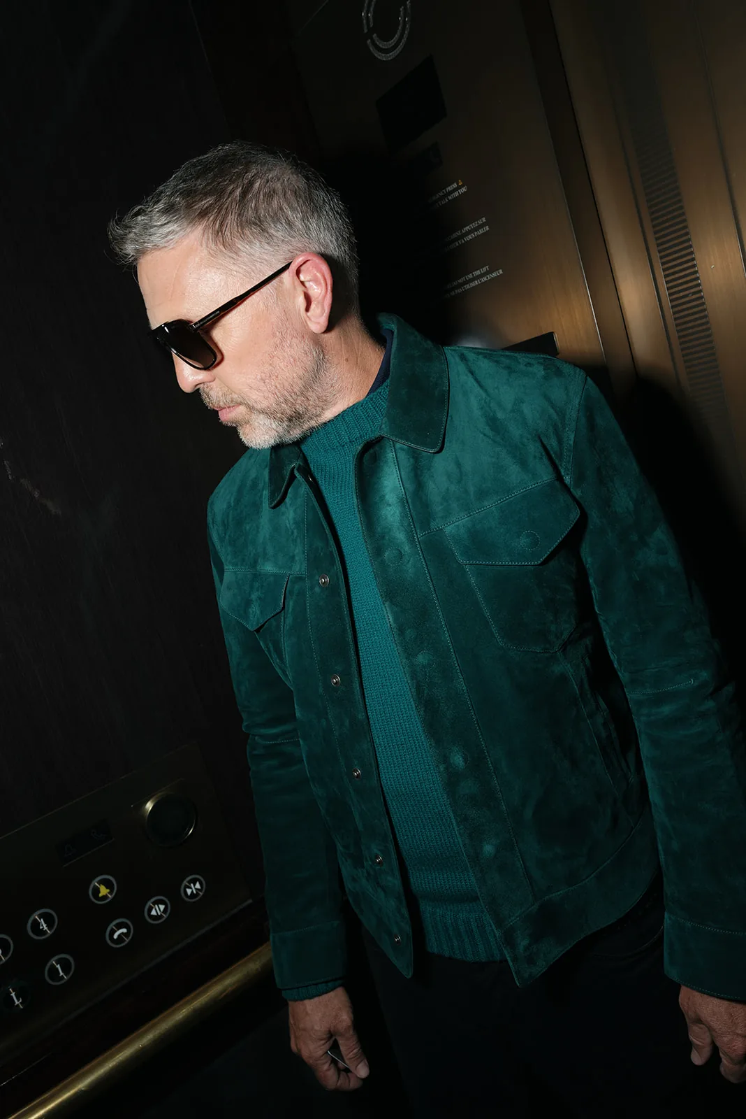 Portrait of a man wearing Tom Ford against a dark hotel interior