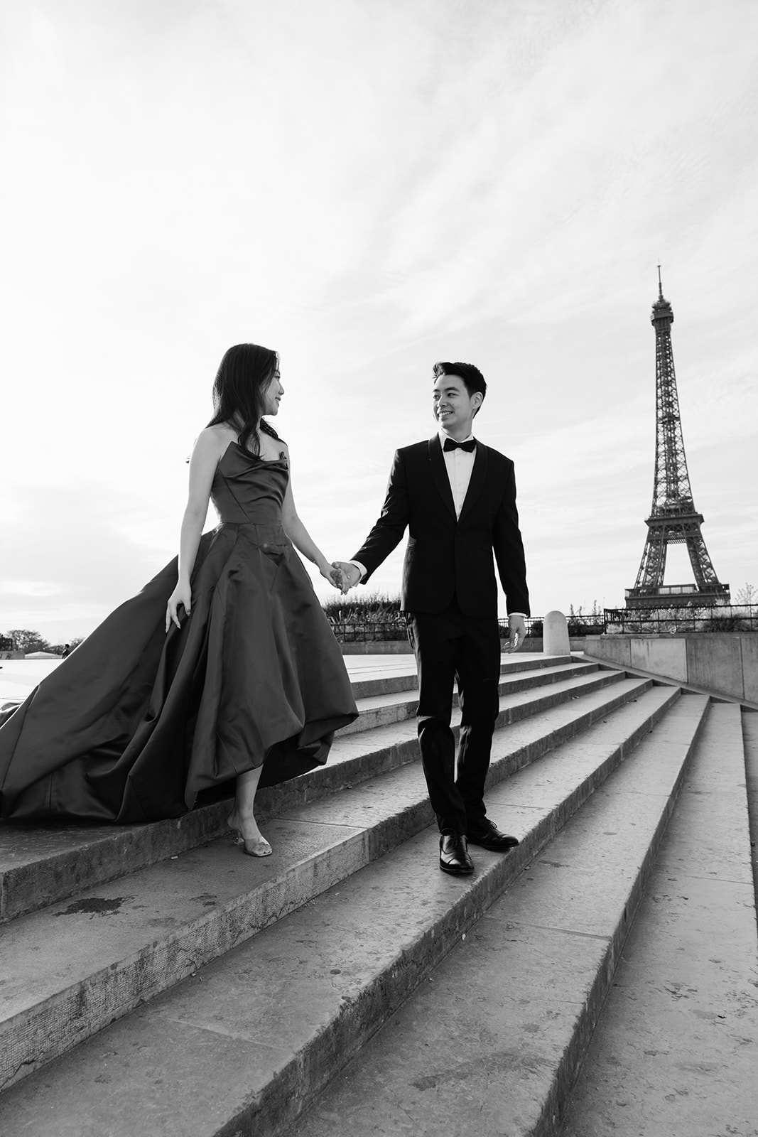 Black and white pre wedding couple walking on the Trocadero steps with the Eiffel Tower in Paris