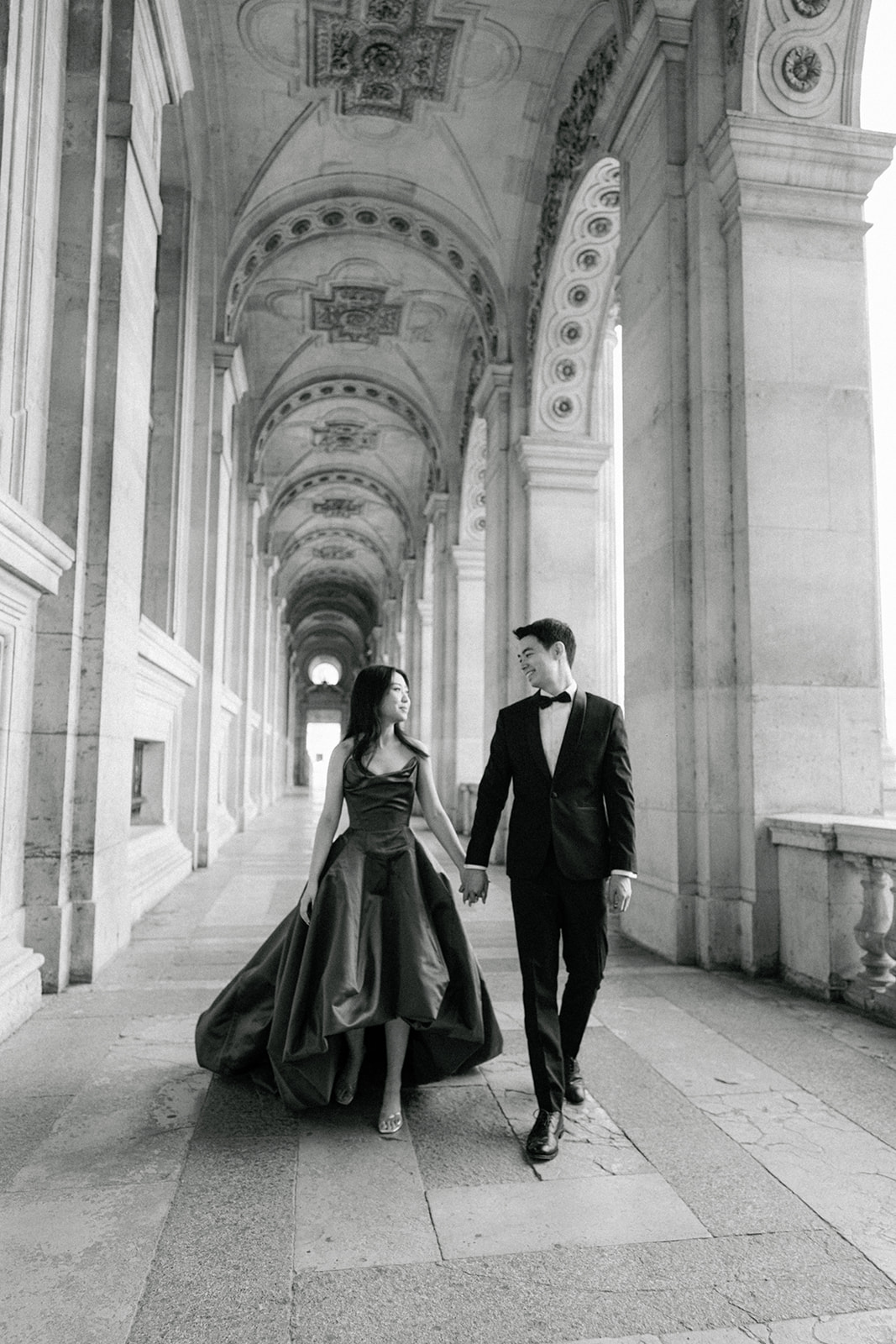 Editorial black and white pre-wedding couple beneath the Louvre colonnade in Paris