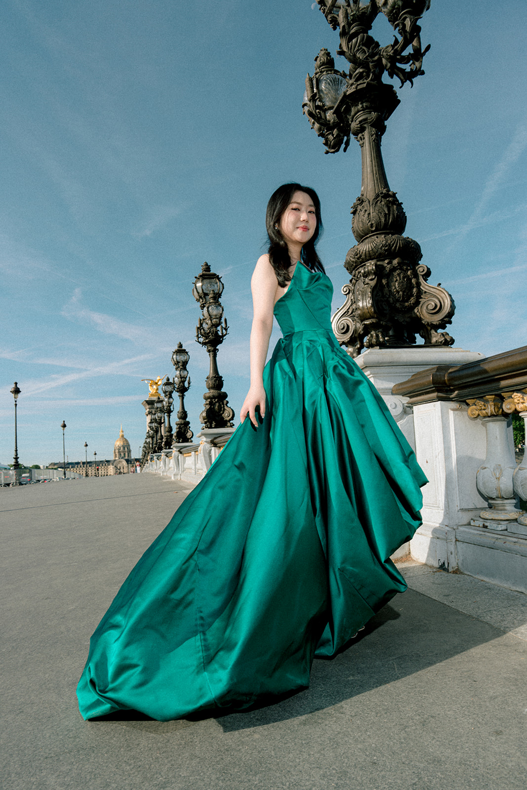 Editorial pre-wedding portrait of a bride in an emerald green gown on Pont Alexandre III in Paris