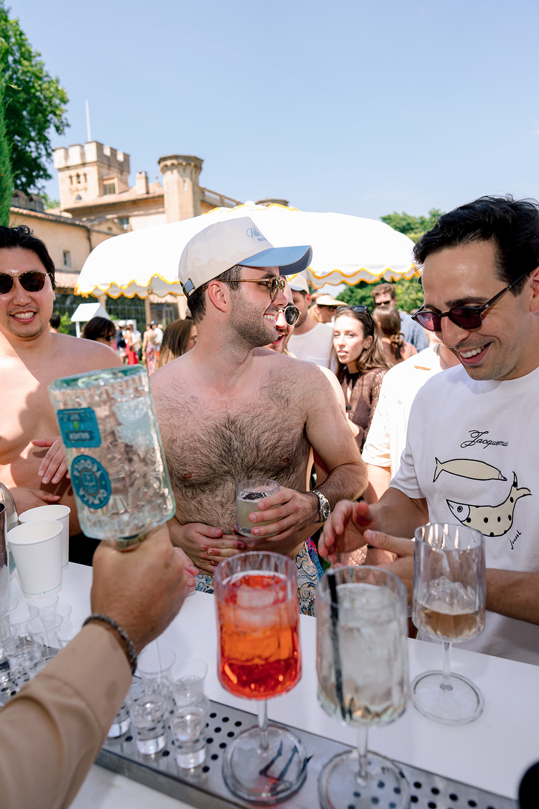 Wedding guests ordering summer cocktails at an outdoor pool party bar in Provence