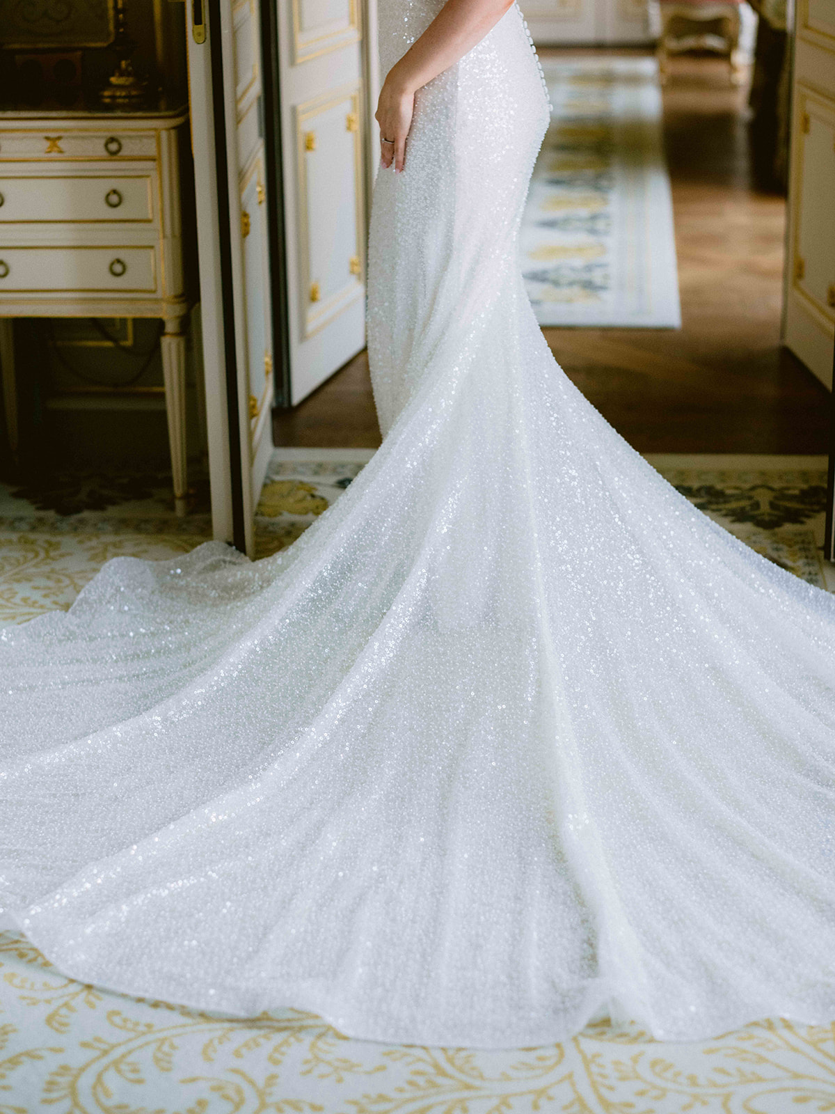 Détail de la traîne scintillante d'une robe de mariée dans une suite parisienne
