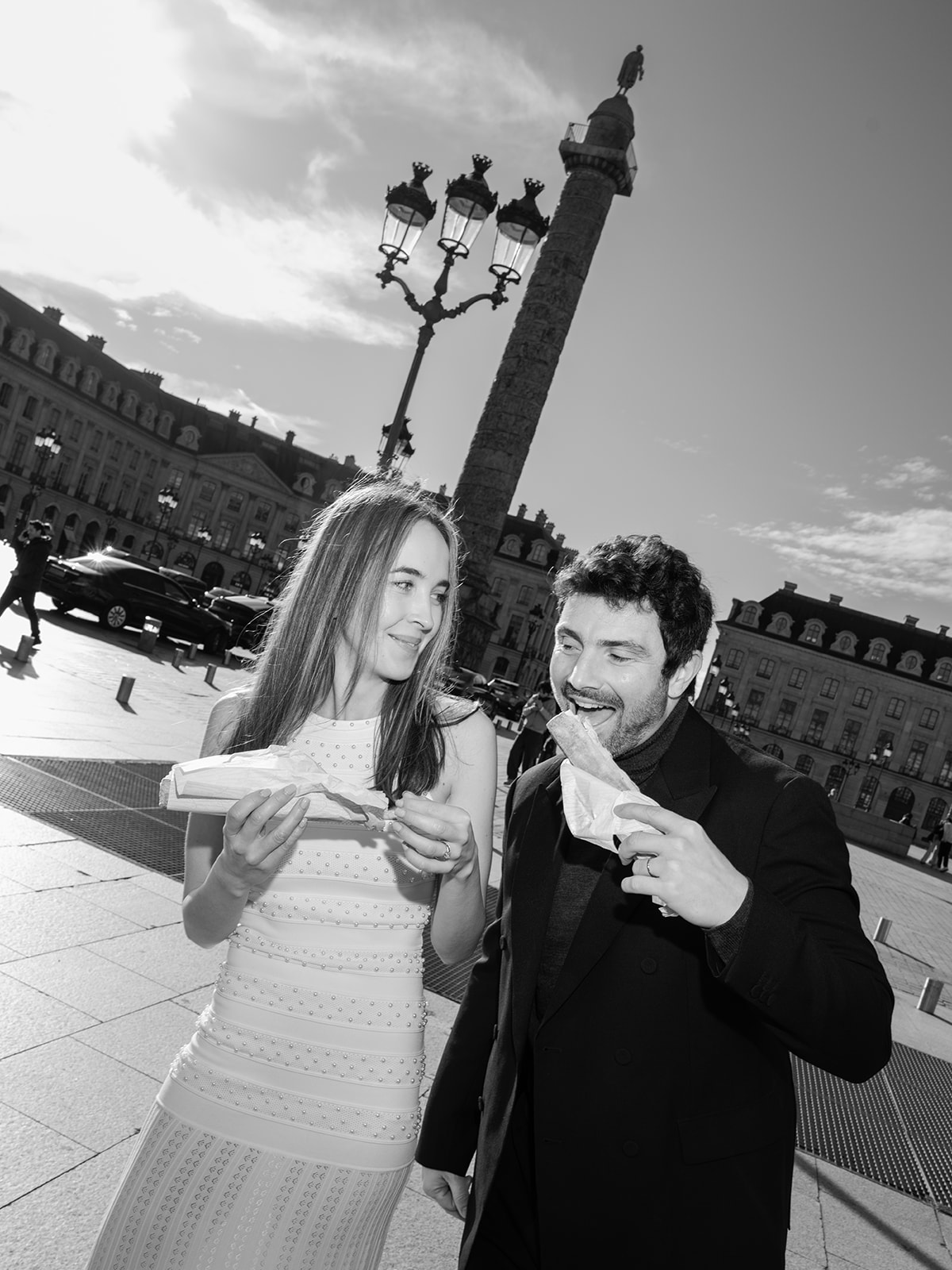 Black-and-white editorial couple sharing French pastries on Place Vendôme