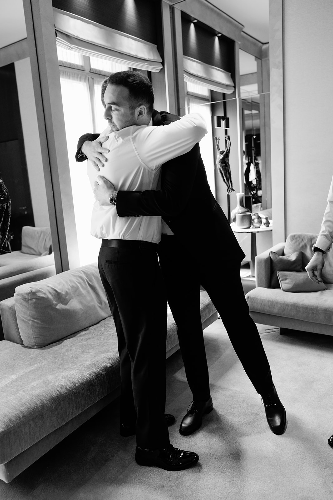 Groom embracing a friend during the wedding preparations at the Ritz Paris