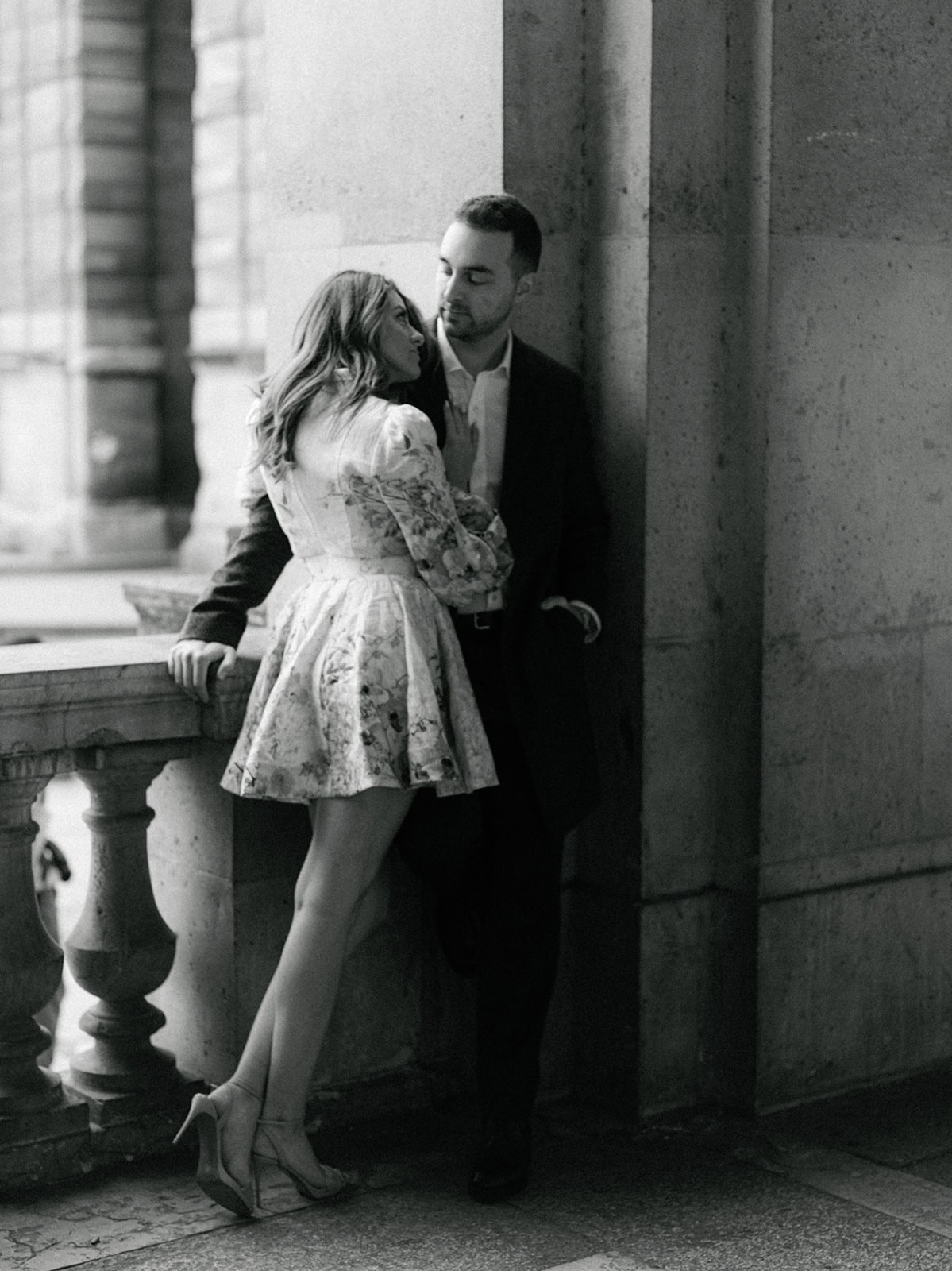 Black-and-white couple portrait beneath the Louvre colonnade during a Paris pre-wedding