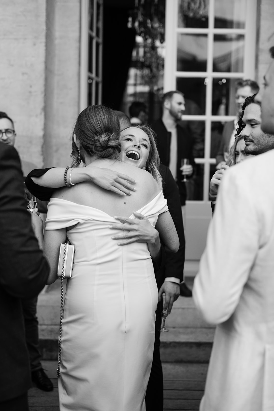 Black-and-white candid embrace between guests at a Paris welcome dinner