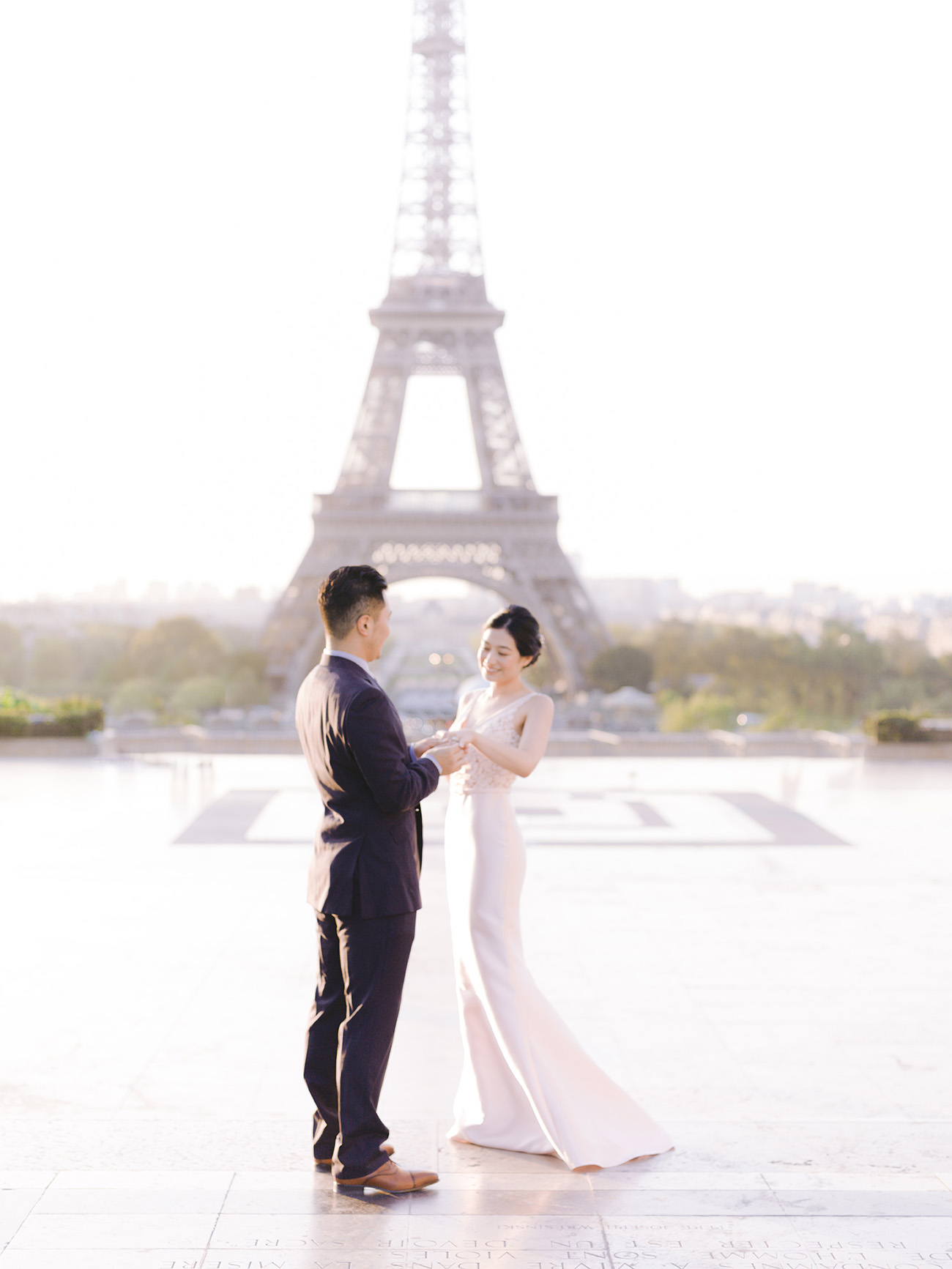 Man putting veil on woman at Eiffel Tower in Paris