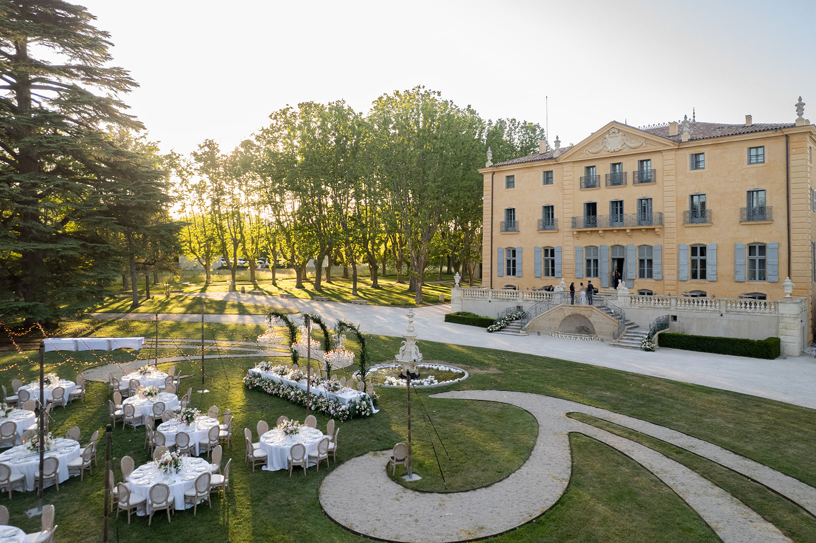 Outdoor wedding dinner at sunset in the gardens of Château de Fonscolombe