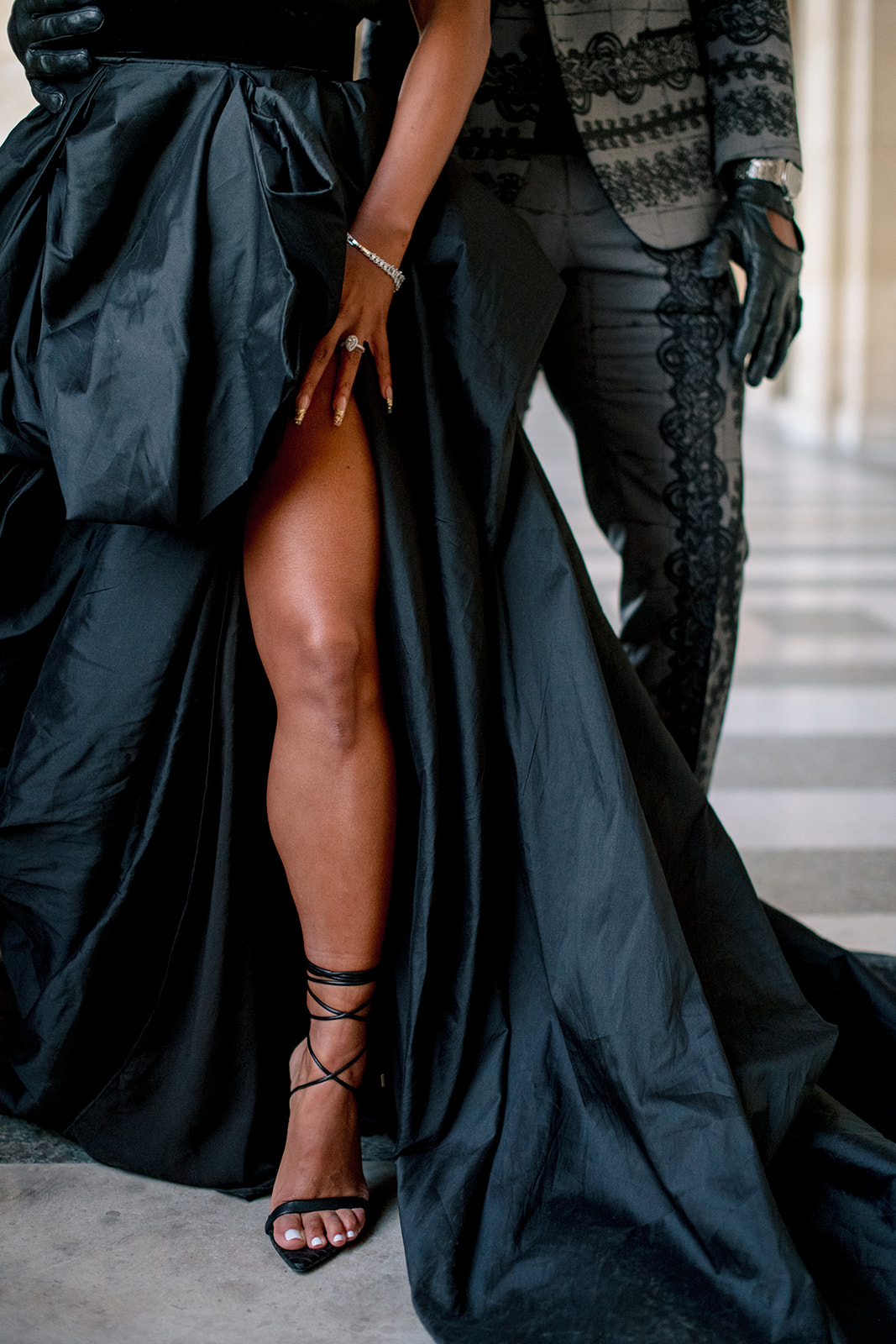 Fashion detail of Candice Craig’s black gown and heels during a Louvre portrait session