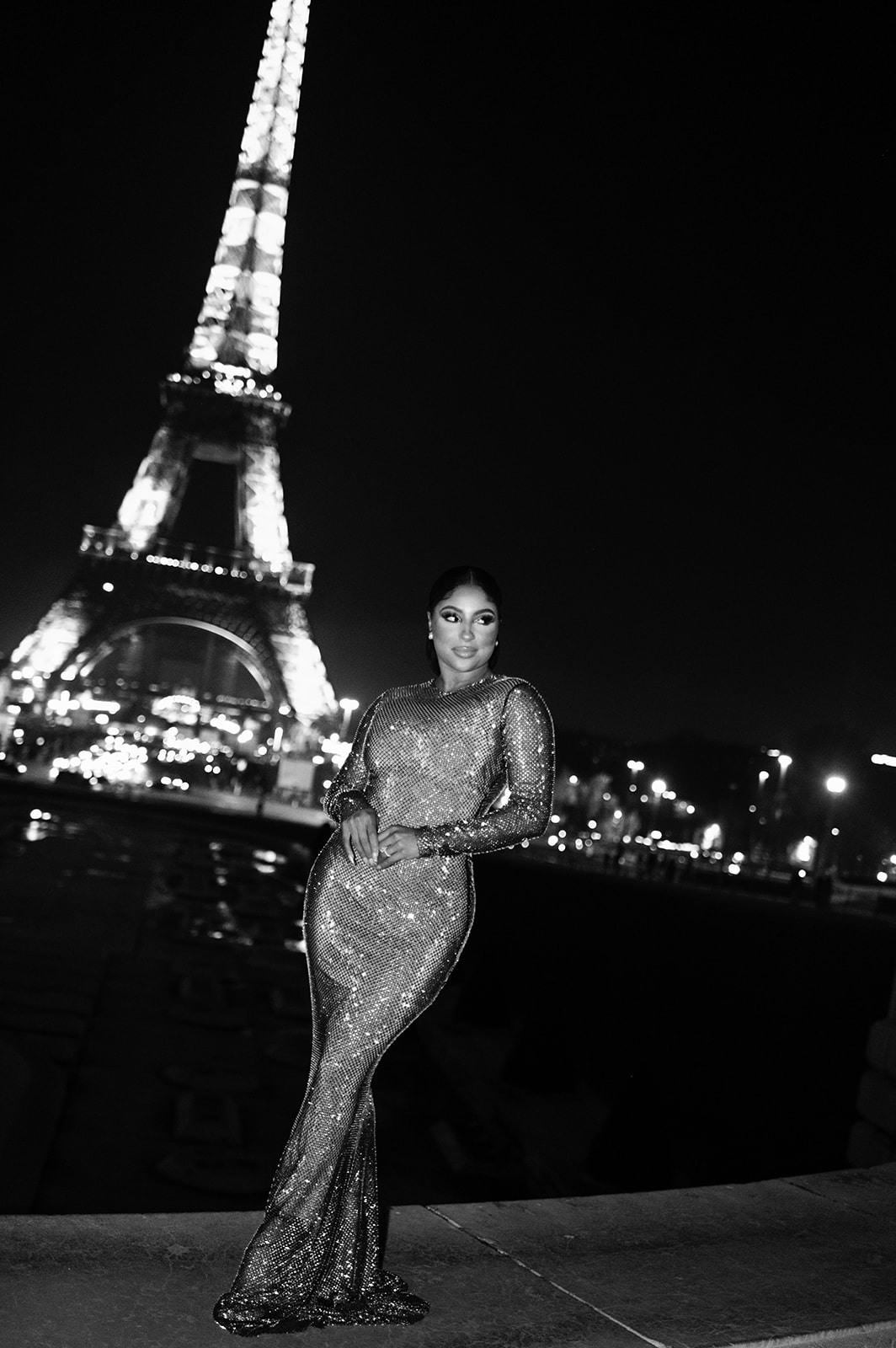 Candice Craig posing in an evening gown with the Eiffel Tower illuminated behind her