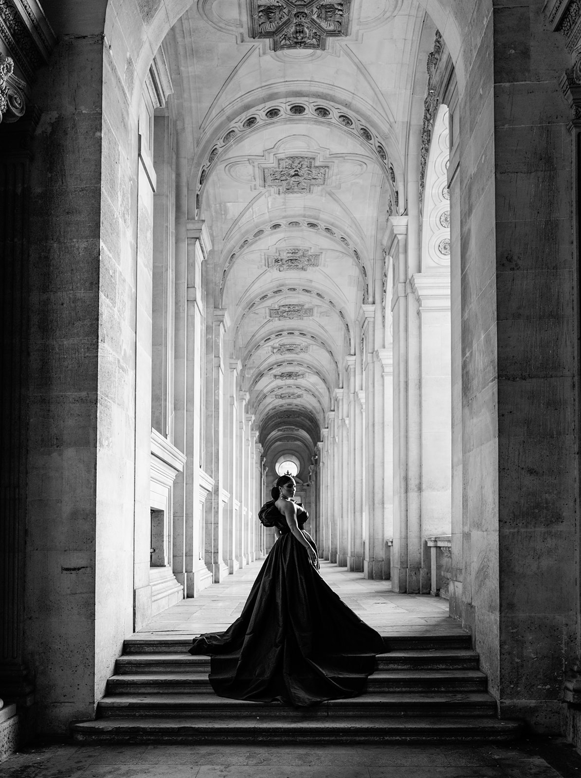 Candice Craig framed beneath the Louvre arcades in a black-and-white editorial portrait