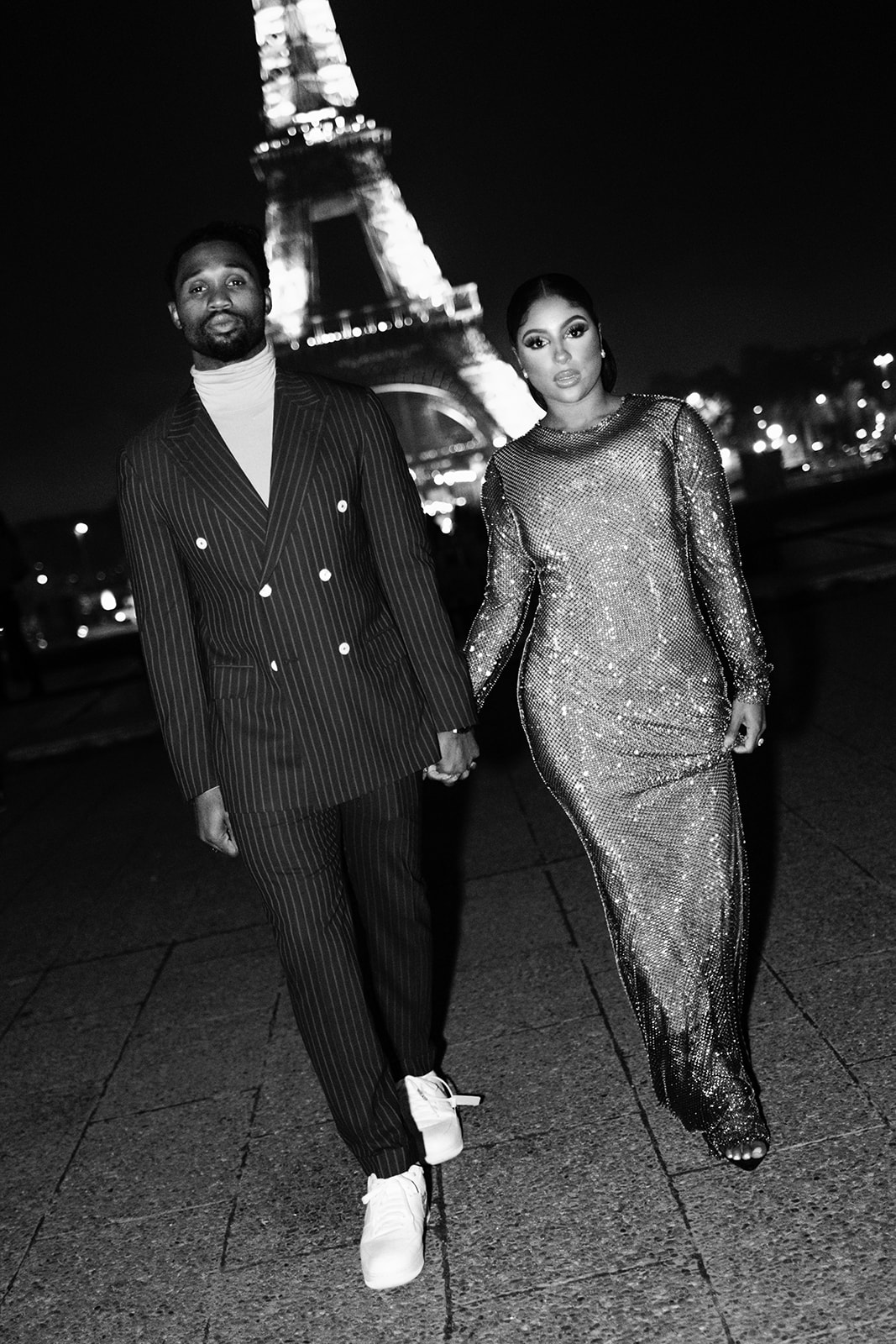Black-and-white photograph of Candice Craig and Omar Bolden walking near the Eiffel Tower at night