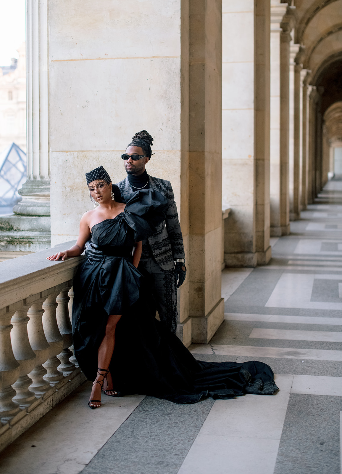 Candice Craig and Omar Bolden posing beside a Louvre balcony during their Paris editorial session
