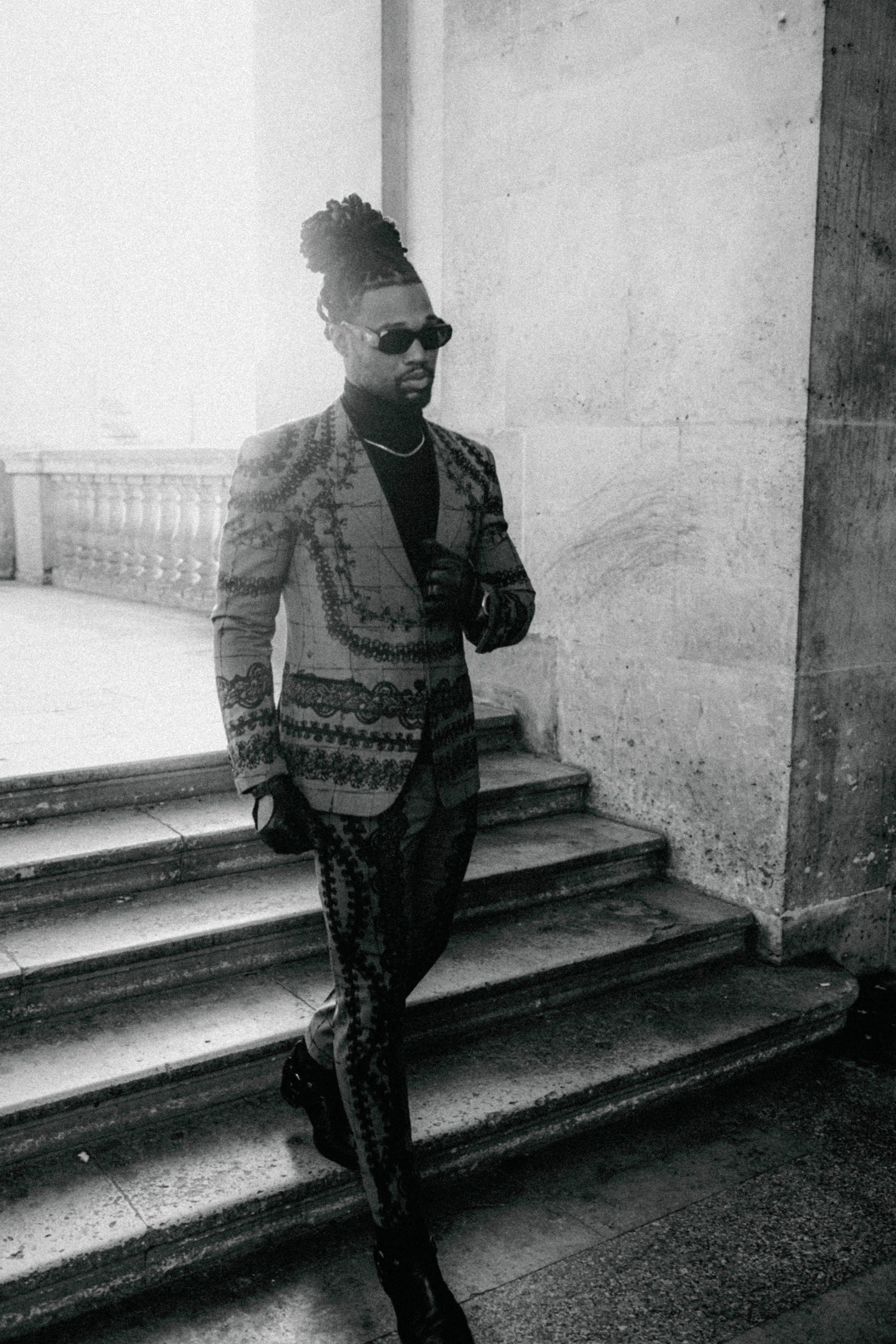 Black-and-white fashion portrait of Omar Bolden beneath the Louvre arcades in Paris