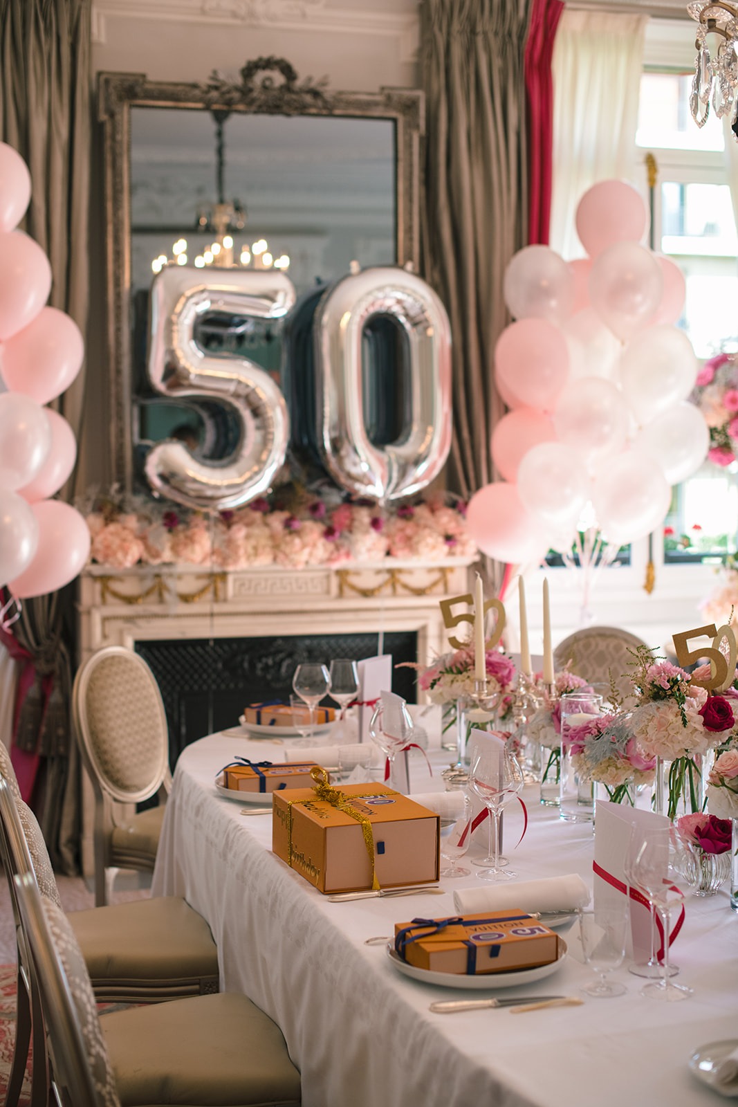 Private 50th birthday table with silver balloons, pink flowers and Louis Vuitton gifts at Hôtel Plaza Athénée Paris