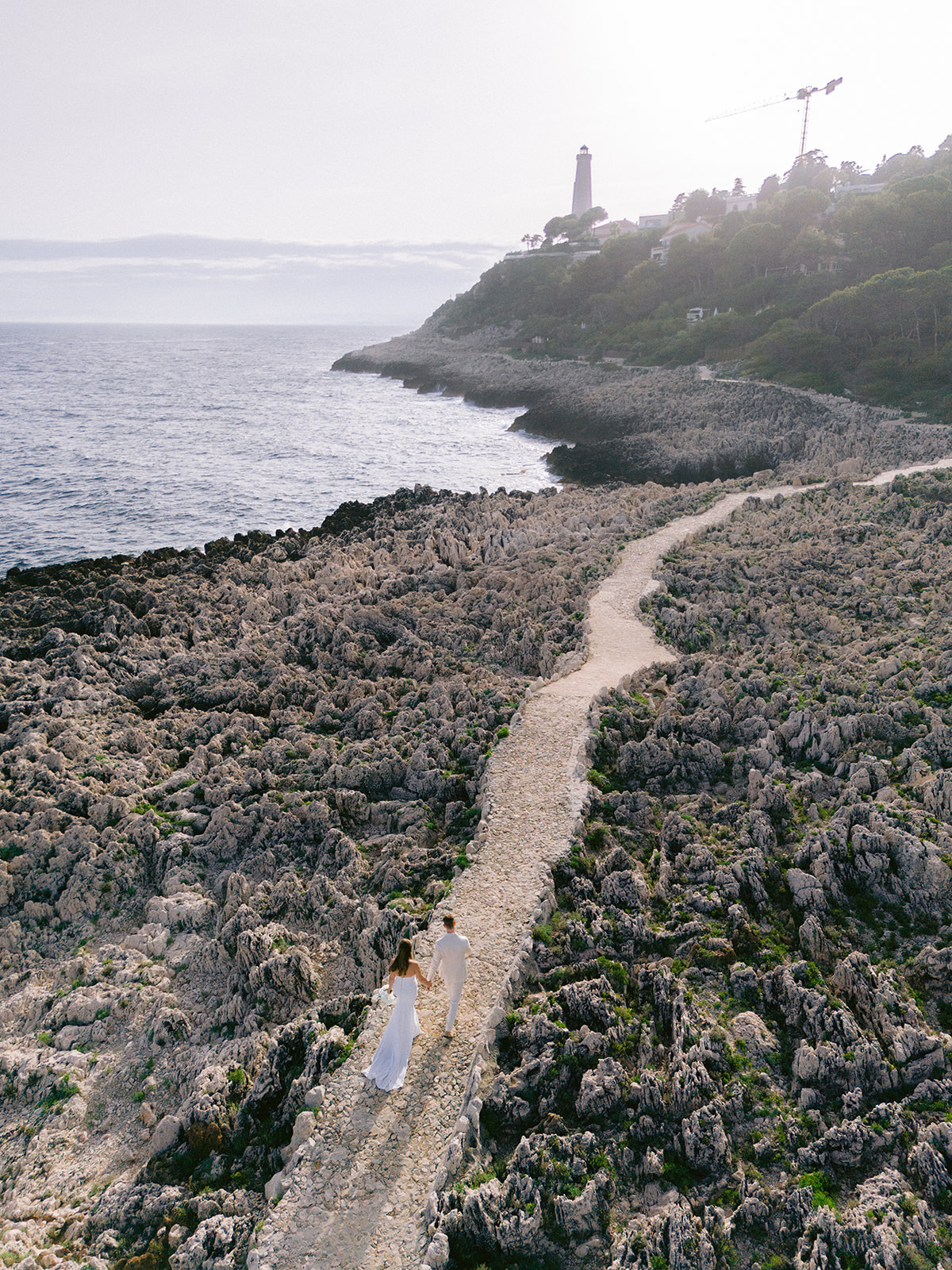 Wedding couple walking along Mediterranean rocks near Grand-Hôtel du Cap-Ferrat