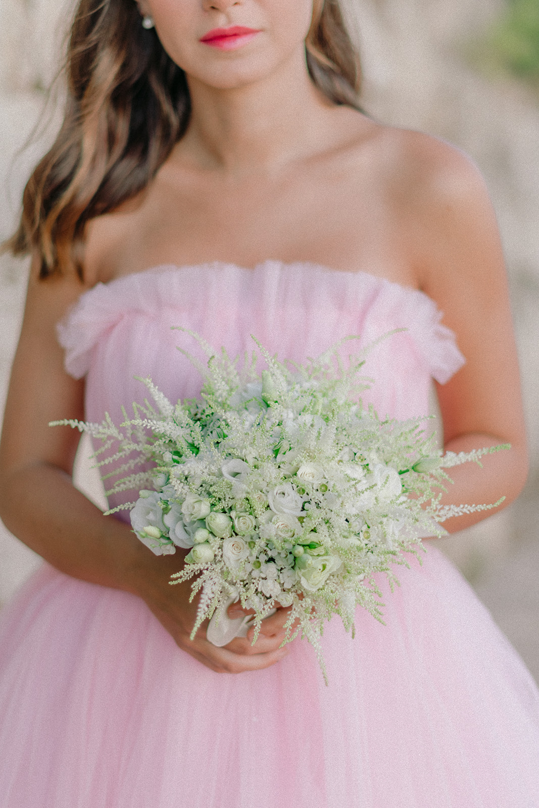 Soft green bridal bouquet held against a pink gown at Grand-Hôtel du Cap-Ferrat