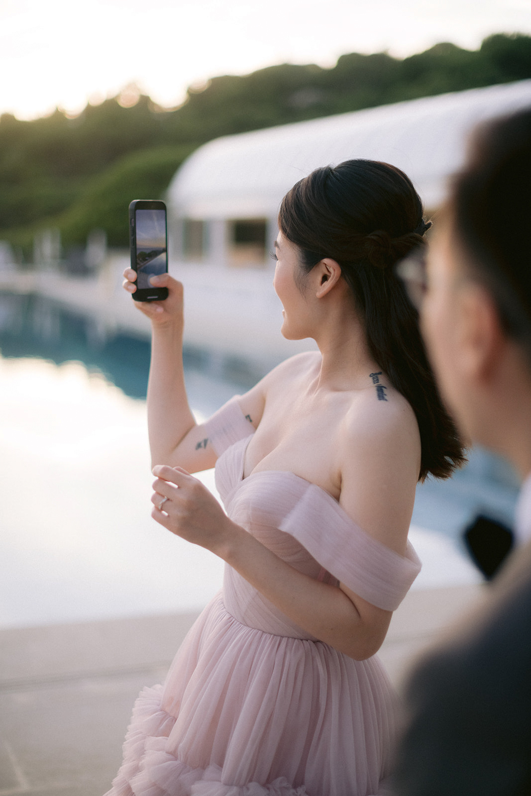 Wedding guest in a pink gown photographing the poolside setting at Grand-Hôtel du Cap-Ferrat