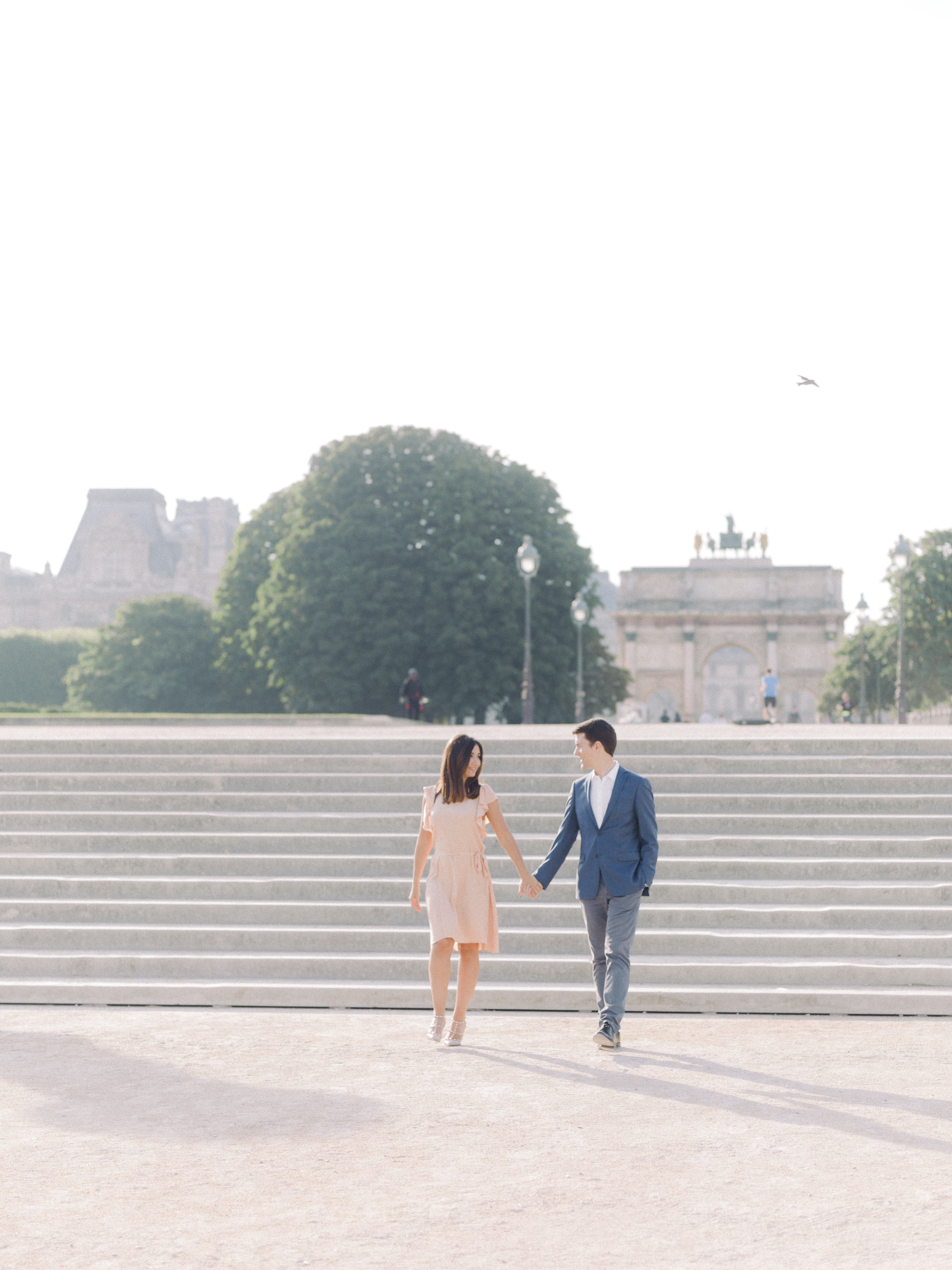 une femlme avec une robe rouge court sur la place du liuvre