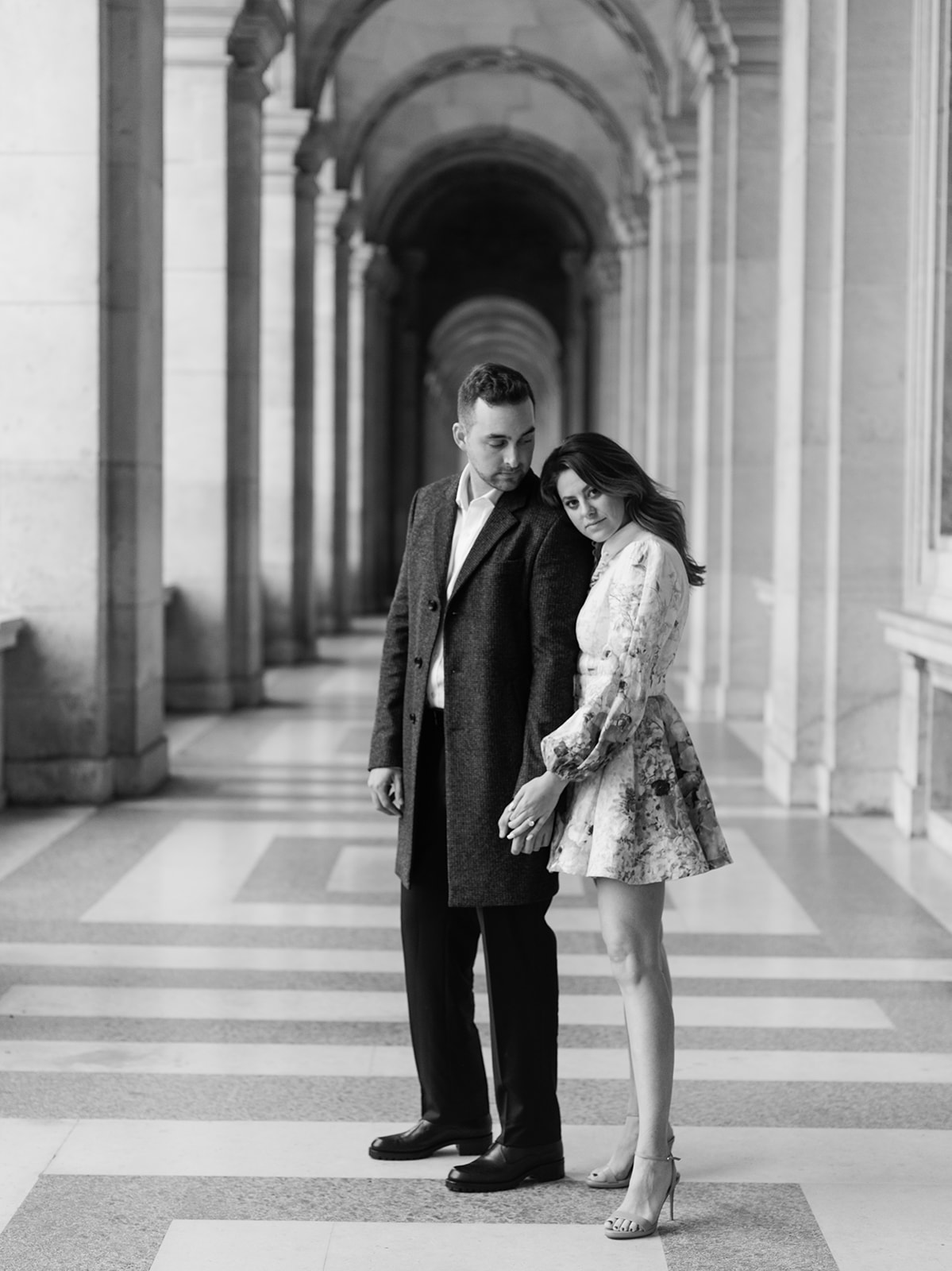 Black-and-white editorial couple portrait beneath the Louvre colonnade
