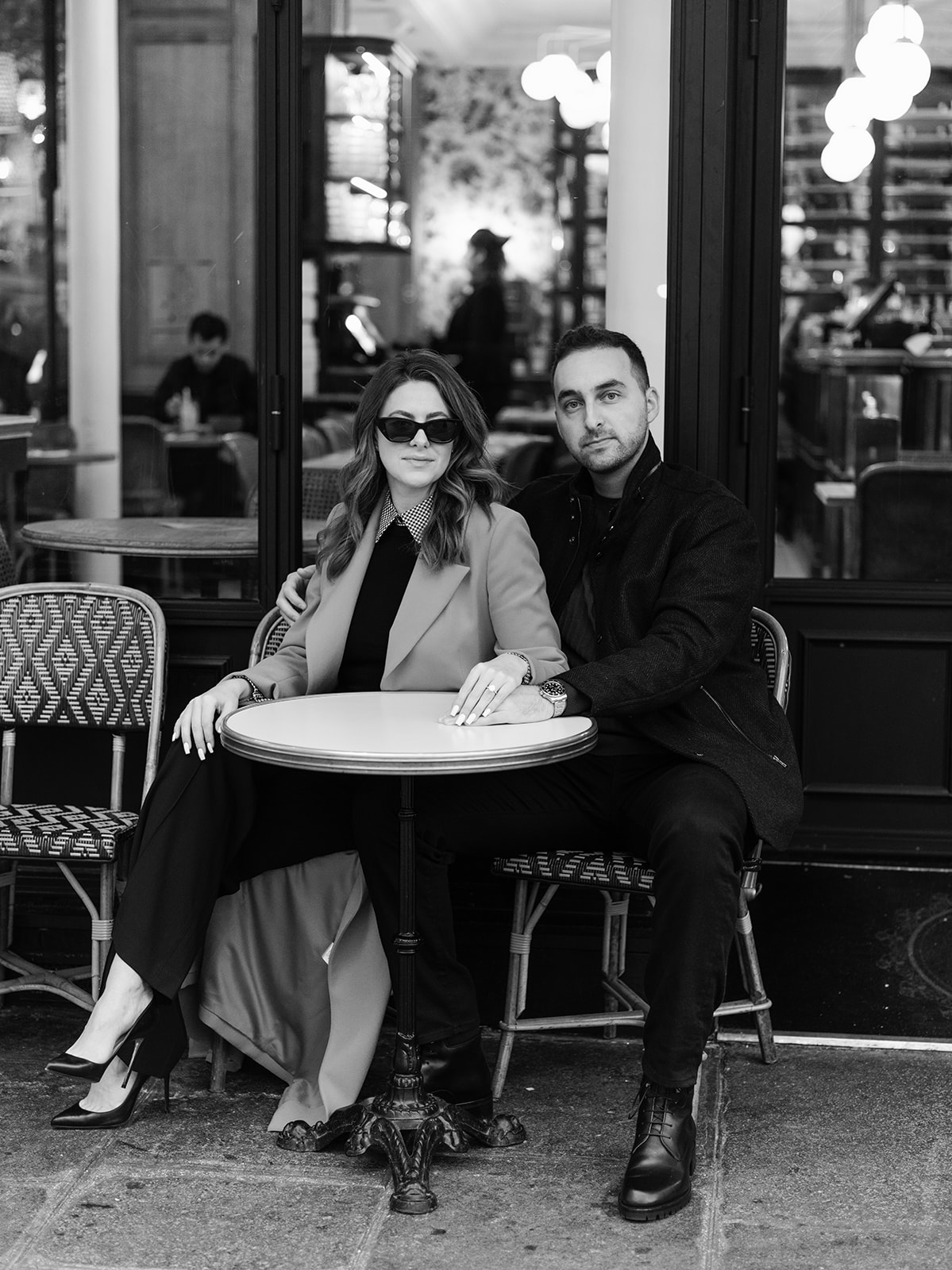 Black-and-white editorial portrait of an American couple seated outside a Paris café