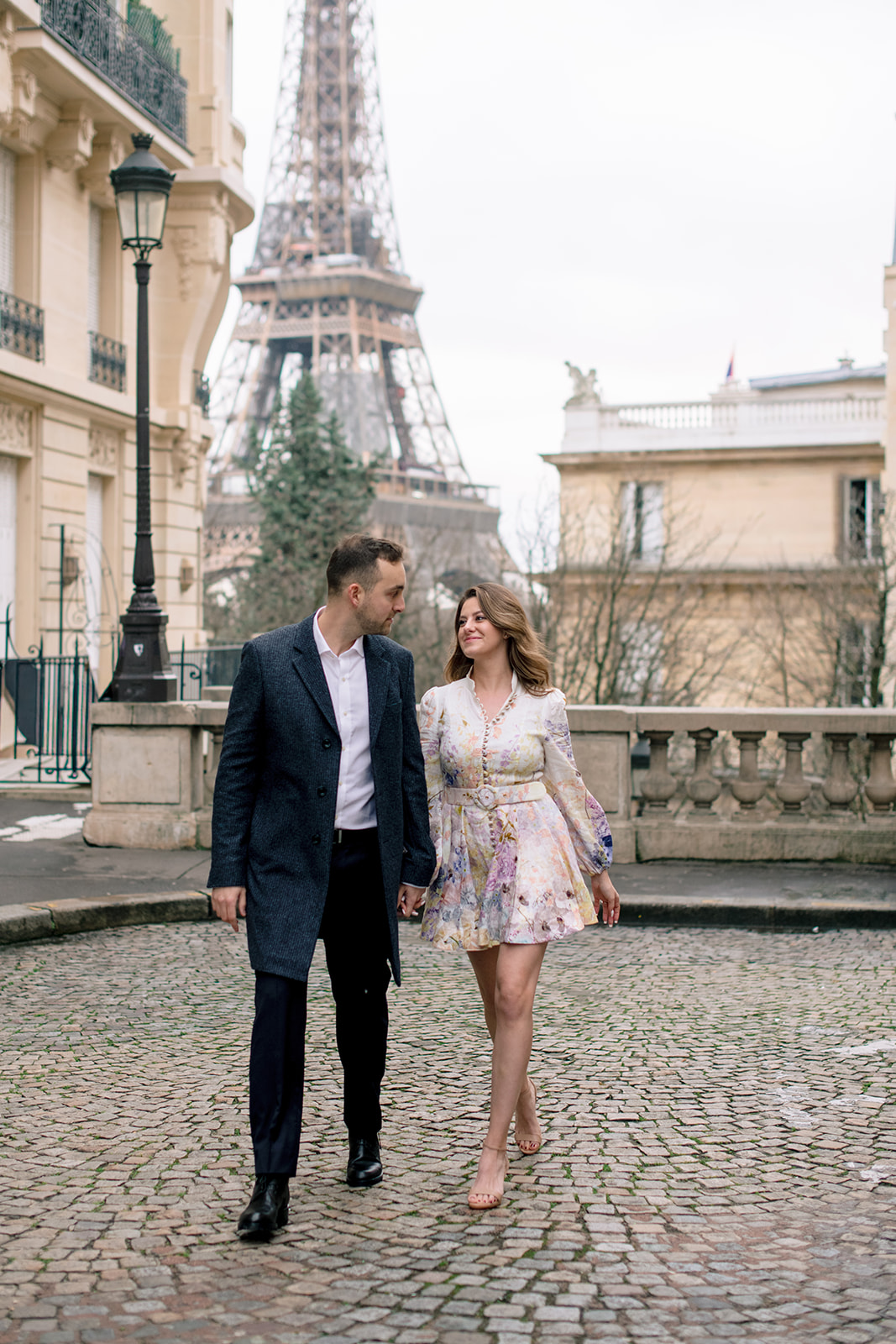 Editorial photograph of a couple walking through Paris near the Eiffel Tower