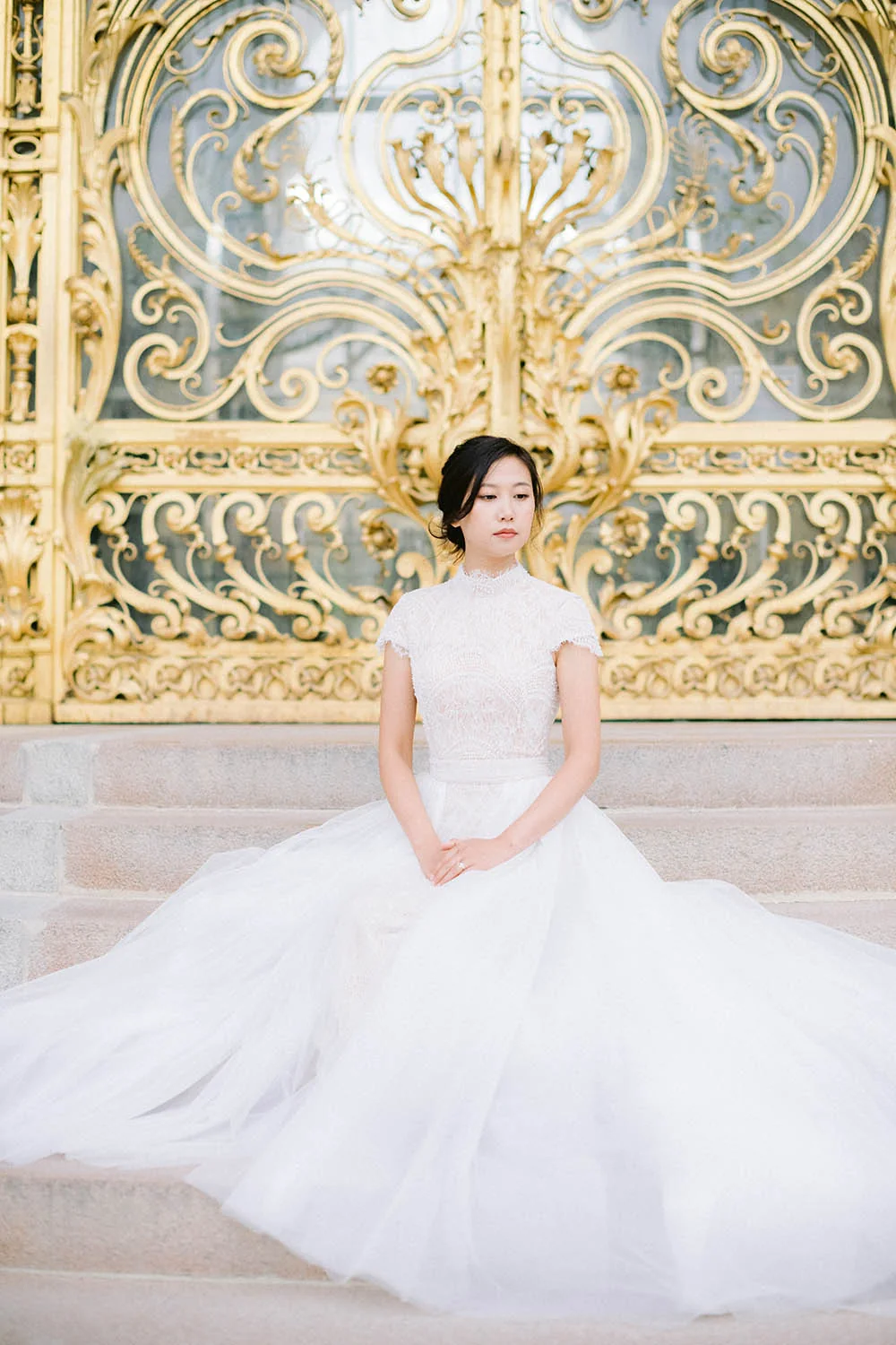 Bride in an Ersa Atelier dress in front of the golden gate at Petit Palais