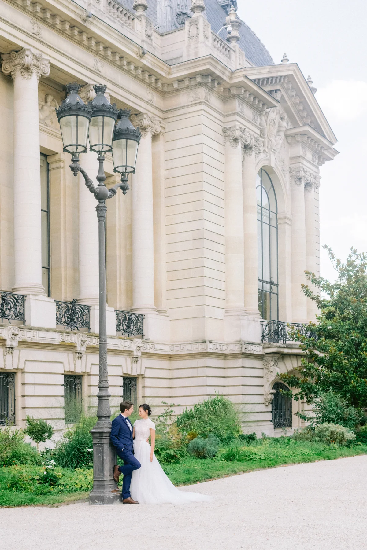 Couple portrait beside the stone facade of Petit Palais in Paris