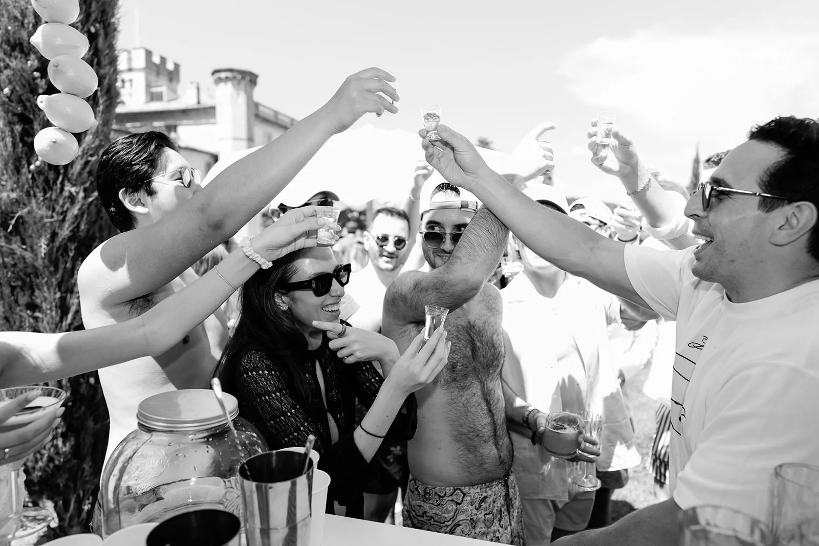 Wedding guests sharing a tequila toast in black and white at Villa Baulieu