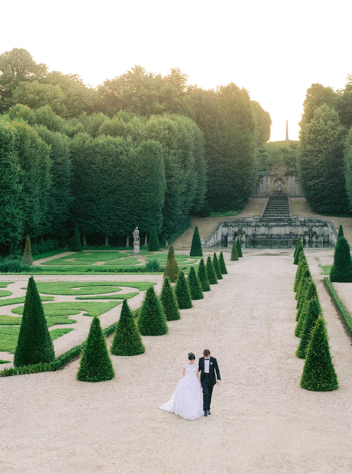 Wedding couple walking through the formal gardens of Château de Villette near Paris