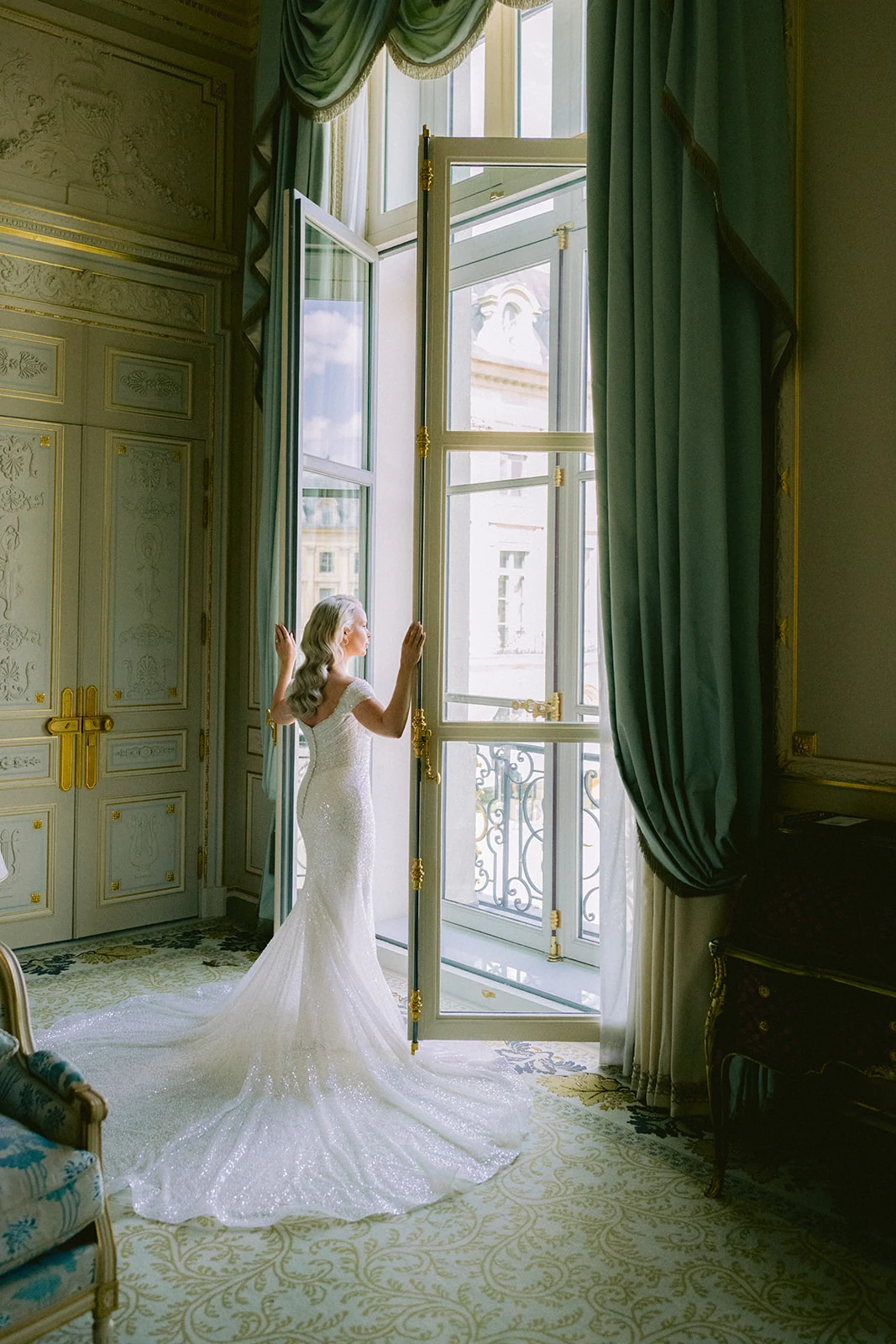 Bride opening the windows of her suite before a luxury Ritz Paris wedding
