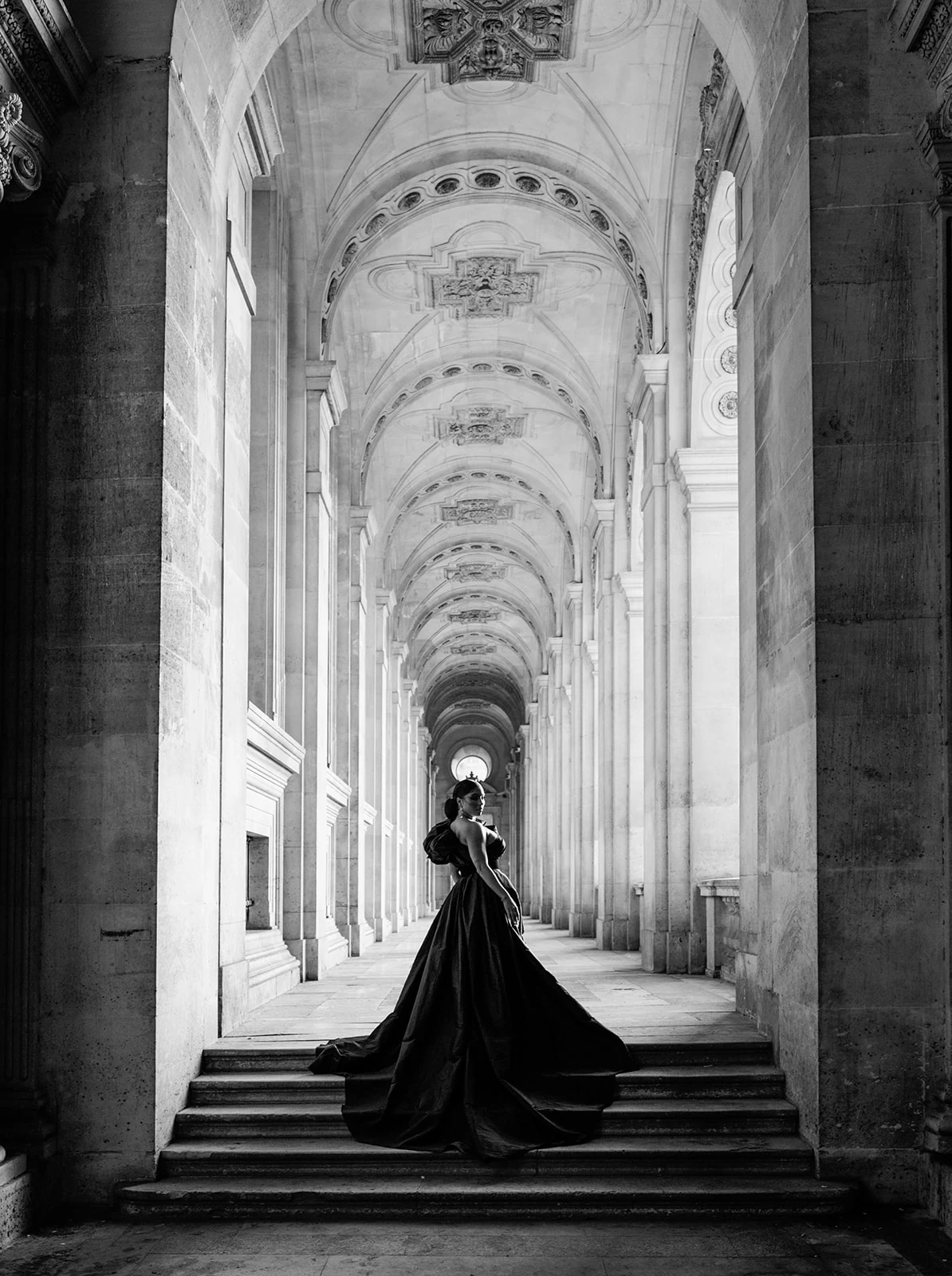 Candice Craig framed beneath the Louvre arcades in a black-and-white editorial portrait