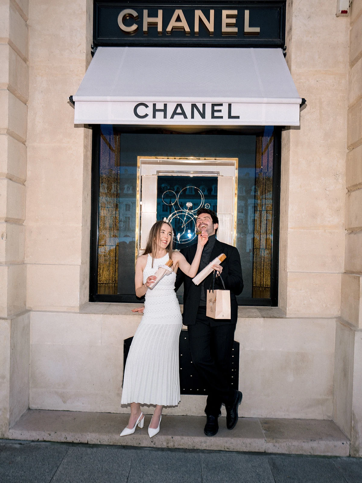 Playful editorial couple portrait with Paris pastries outside Chanel on Rue Cambon