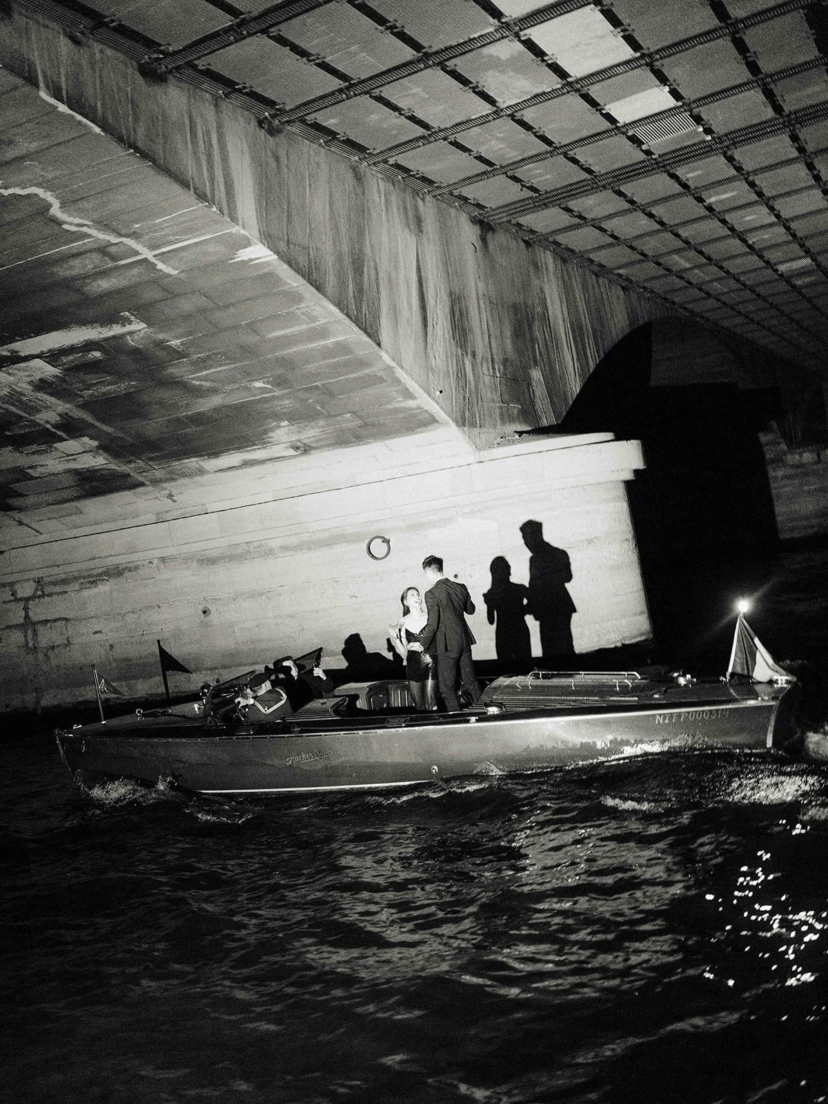Cinematic black and white Paris proposal photo on a private boat beneath a Seine bridge