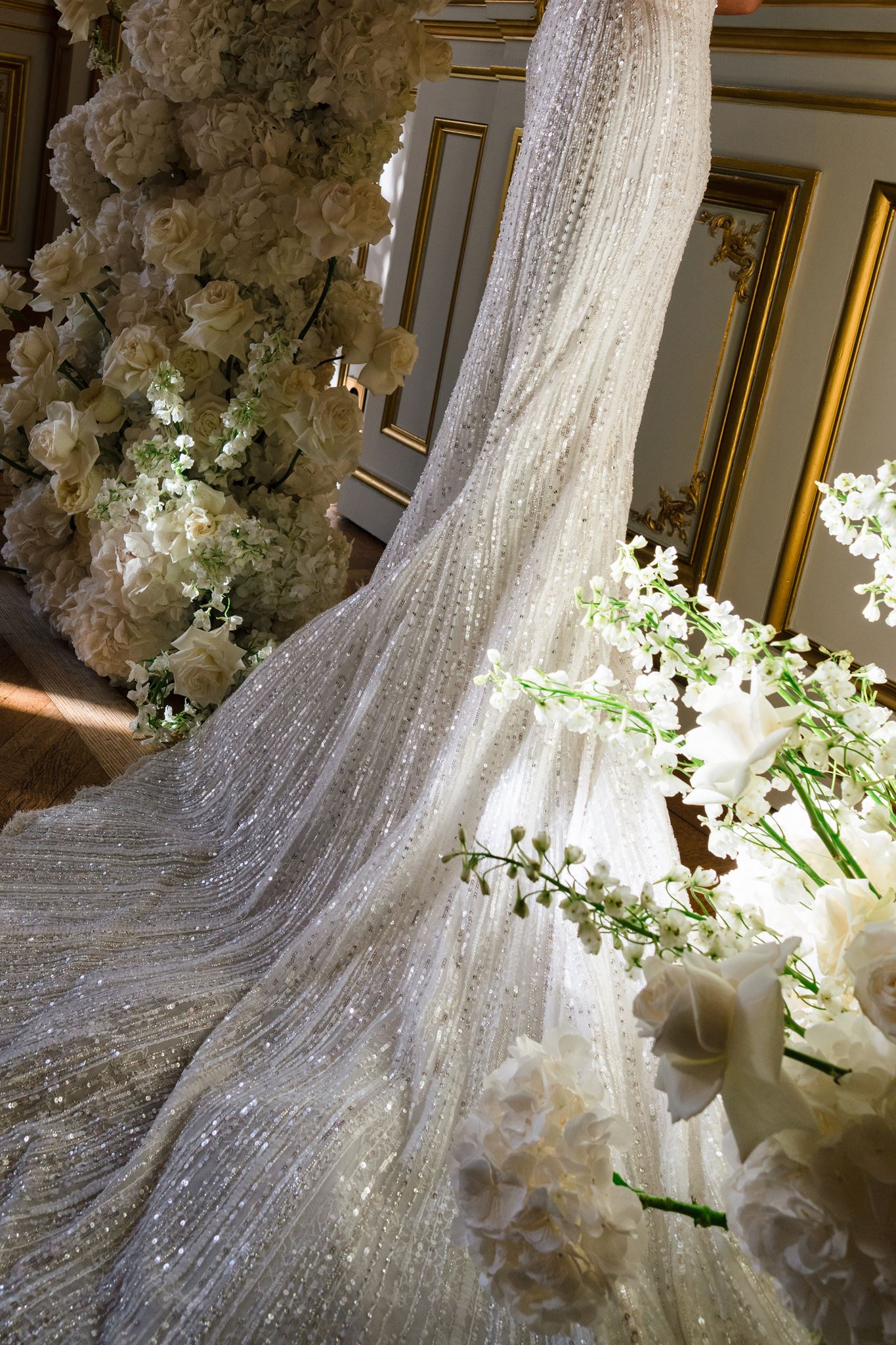 Wedding dress displayed beside a white floral installation during an editorial wedding in Paris