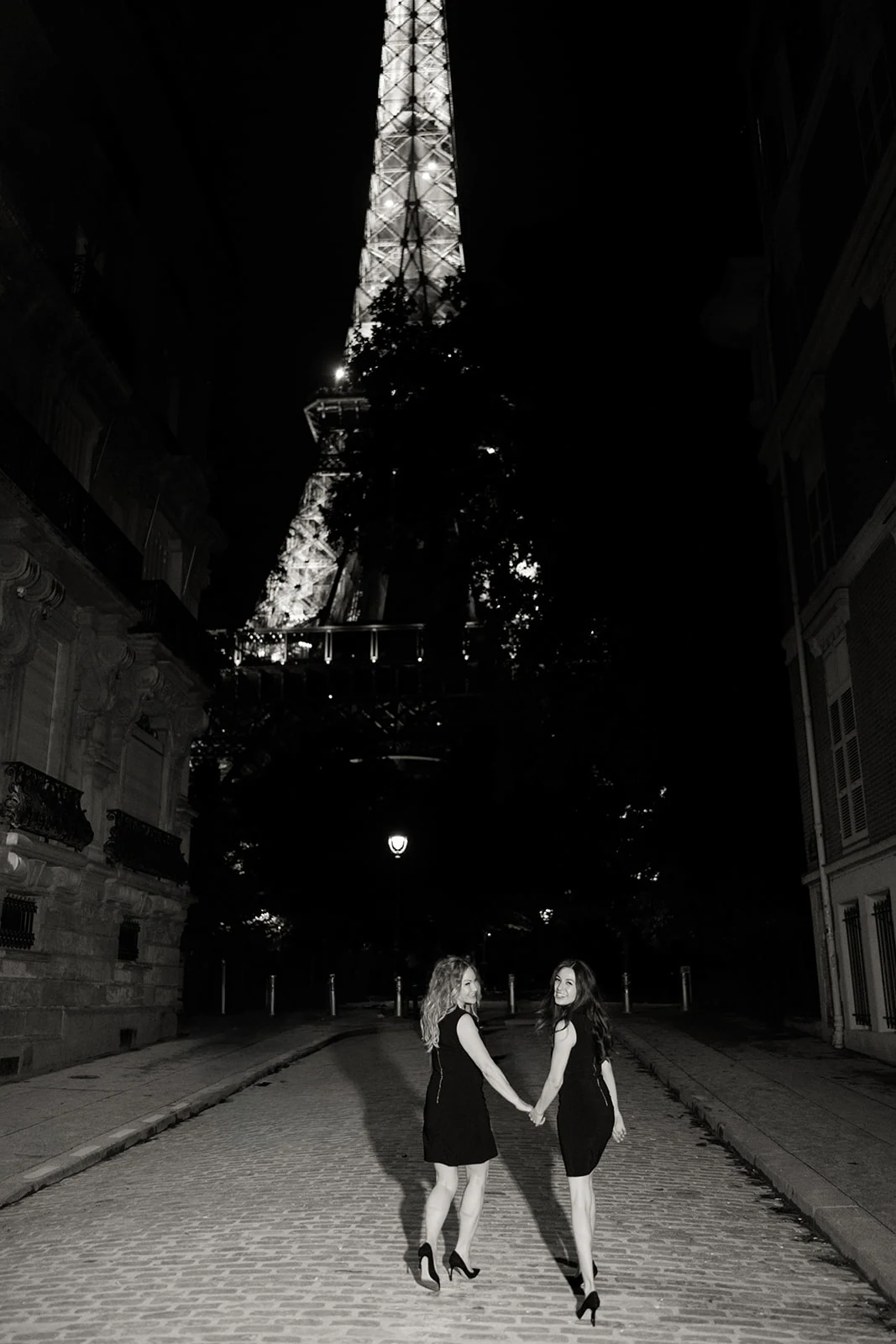 Couple walking hand in hand beneath the Eiffel Tower at night