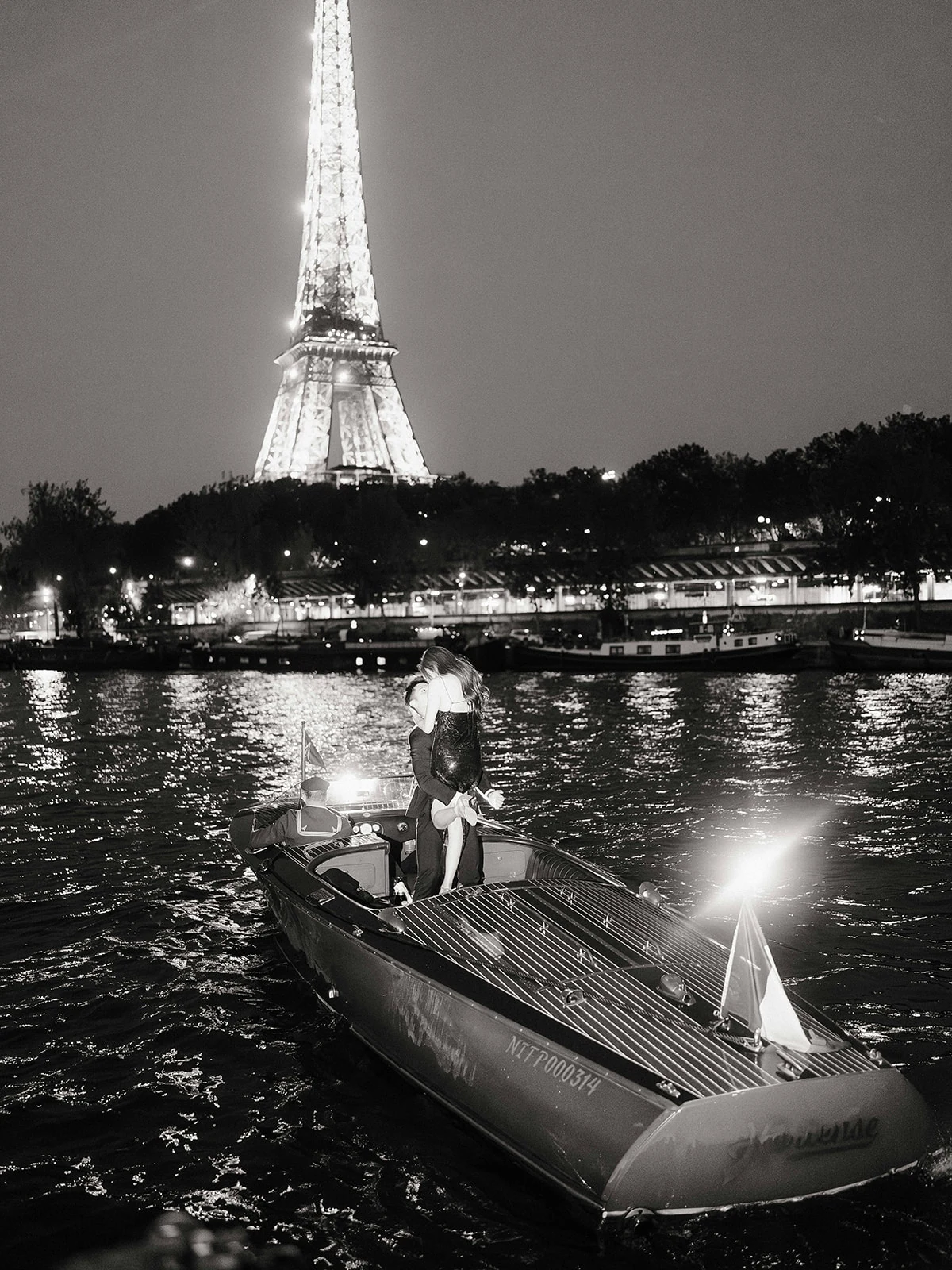 Engaged couple walking with flowers during a nighttime proposal session in Paris