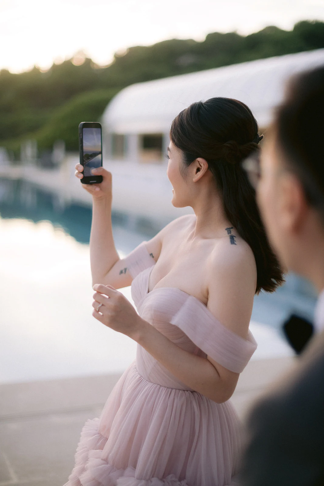 Wedding guest in a pink gown photographing the poolside setting at Grand-Hôtel du Cap-Ferrat
