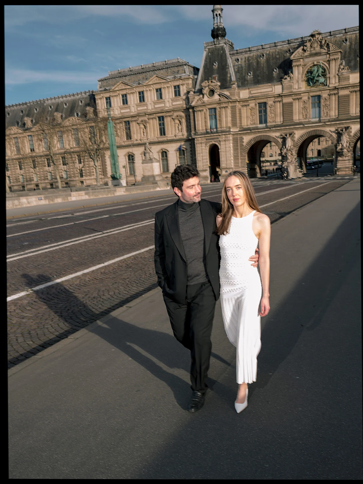Editorial couple walking near the Louvre Museum with a modern fashion-led composition