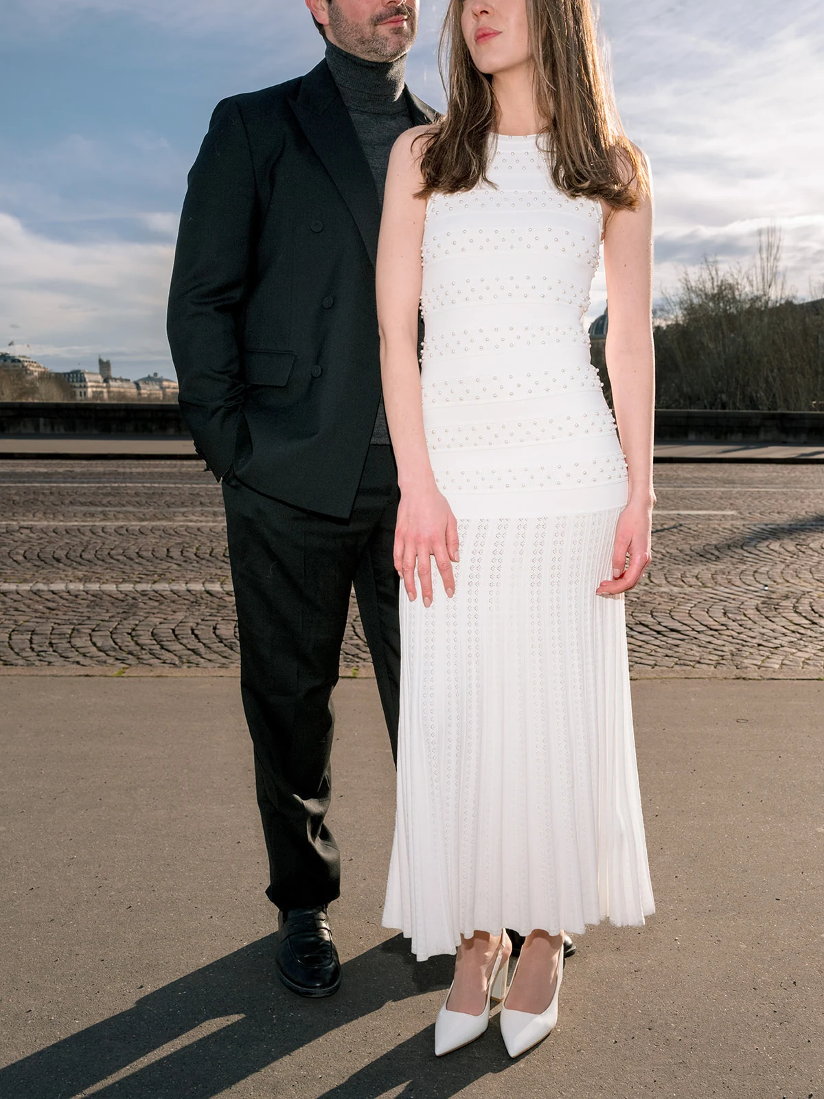 Editorial close-up of a couple in coordinated black-and-white outfits near the Louvre