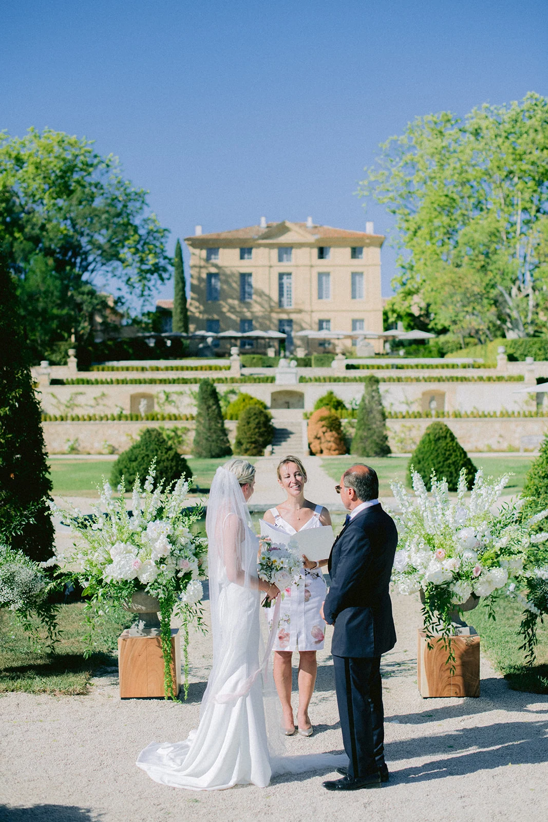 Bride, groom and celebrant during the garden ceremony at Château de la Gaude