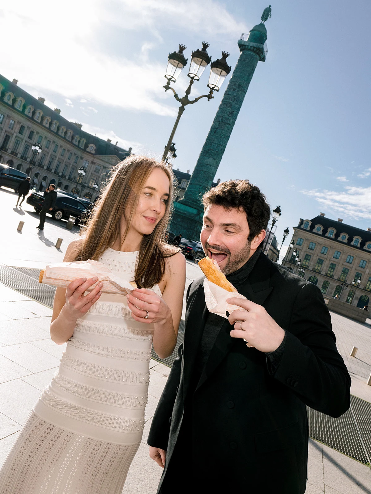 Editorial couple sharing French pastries on Place Vendôme in Paris
