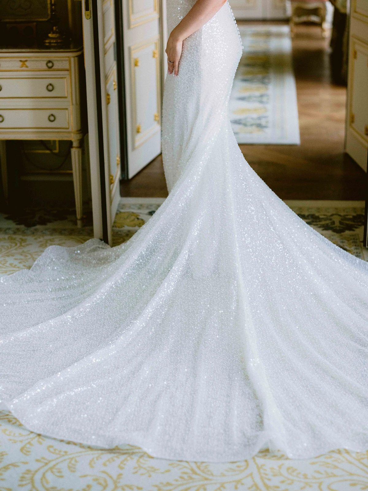 Détail de la traîne scintillante d'une robe de mariée dans une suite parisienne