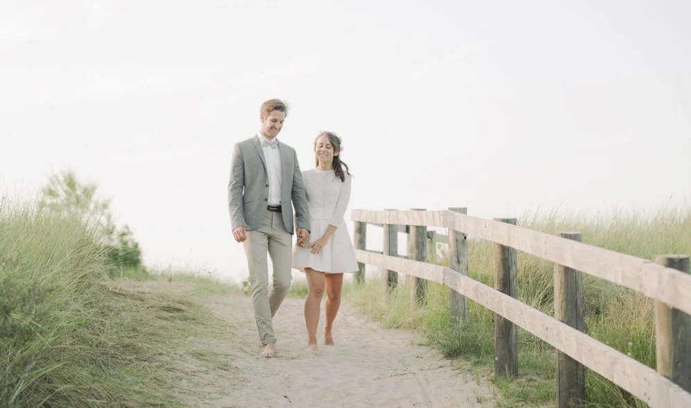 Couple marchant sur le sable pendant une séance d'engagement en Normandie