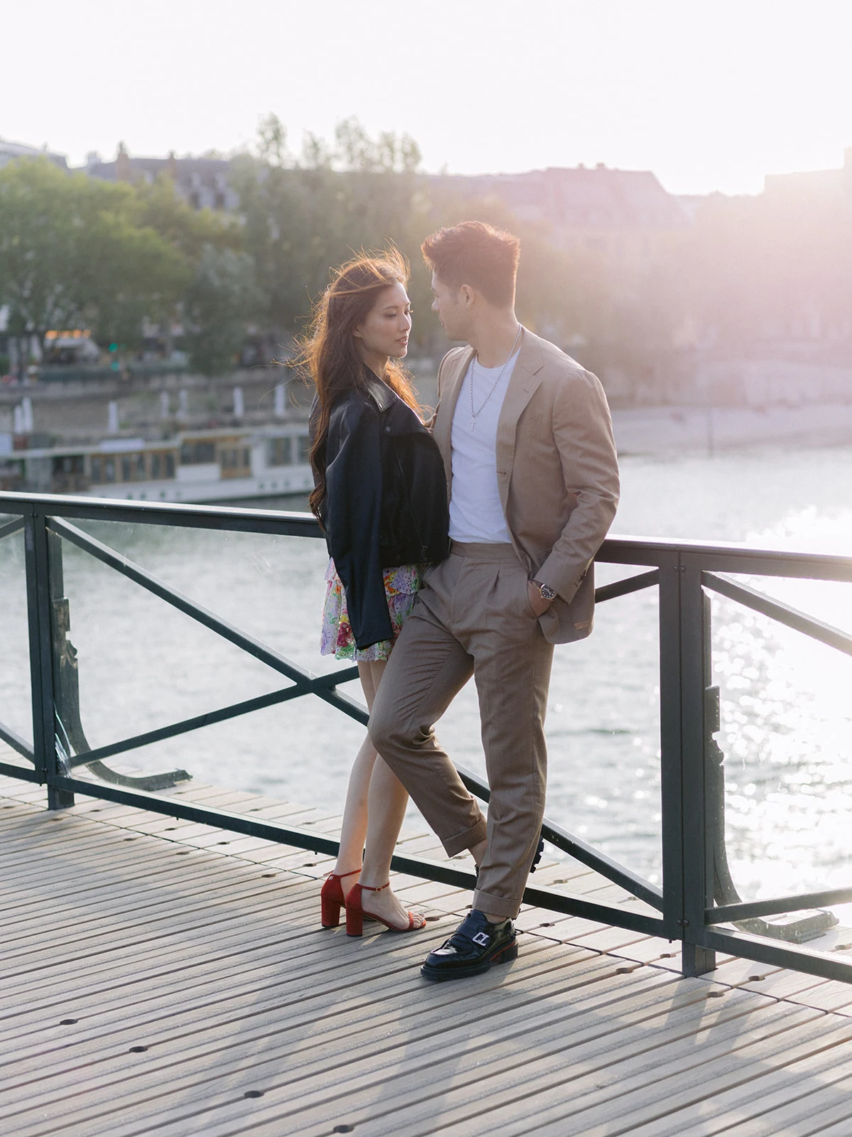 Couple posing beside the Seine River during a Paris engagement session at sunset