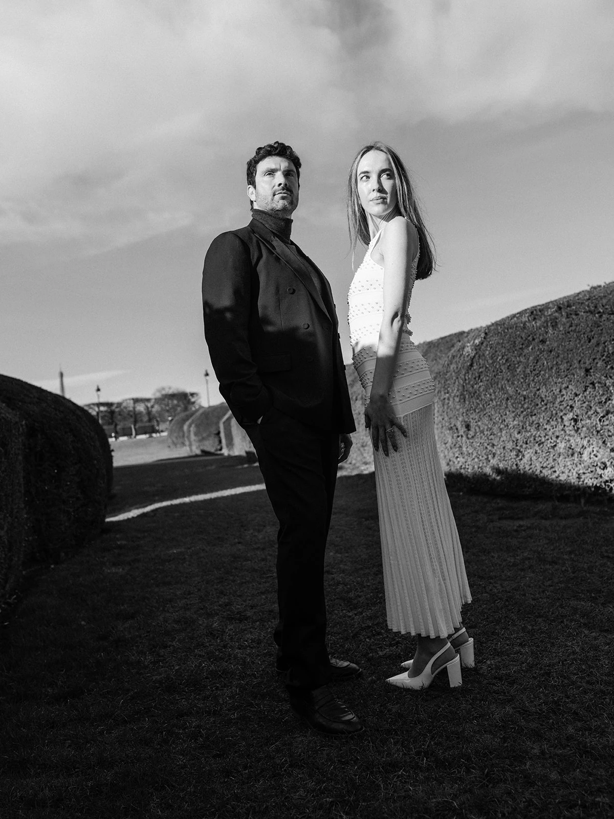 Black-and-white fashion couple portrait between the sculpted hedges of the Tuileries Garden