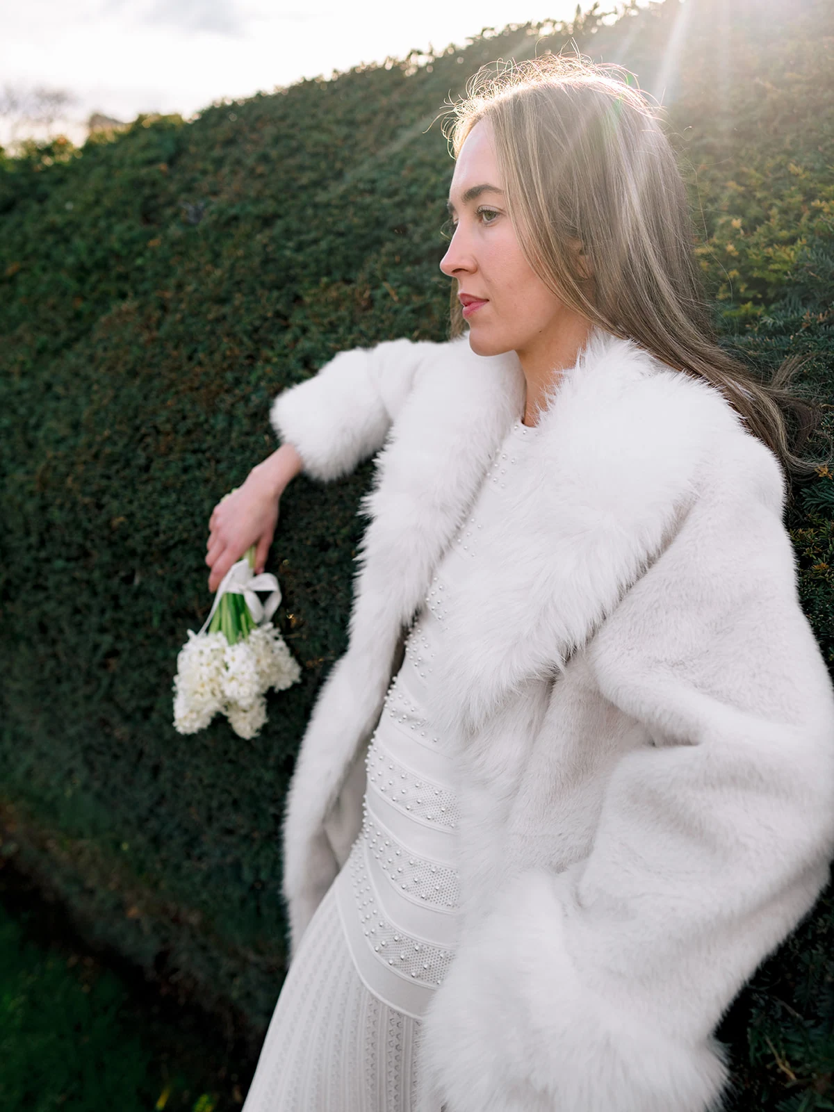 Editorial portrait in a white fur coat with flowers in the Tuileries Garden